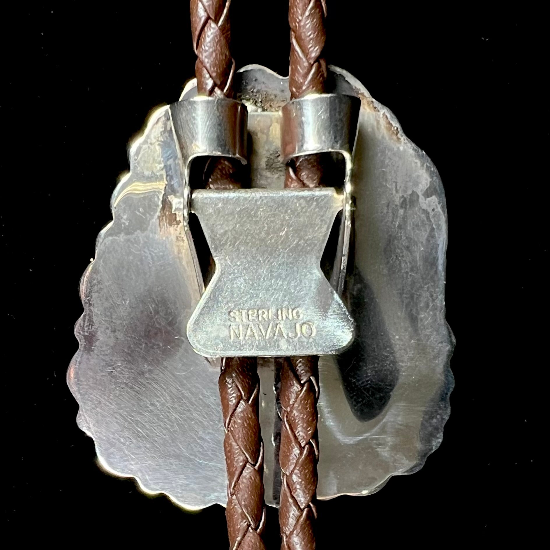 A men's sterling silver, Navajo style bolo tie set with a Pilot Mountain turquoise stone.  The rope is brown leather.