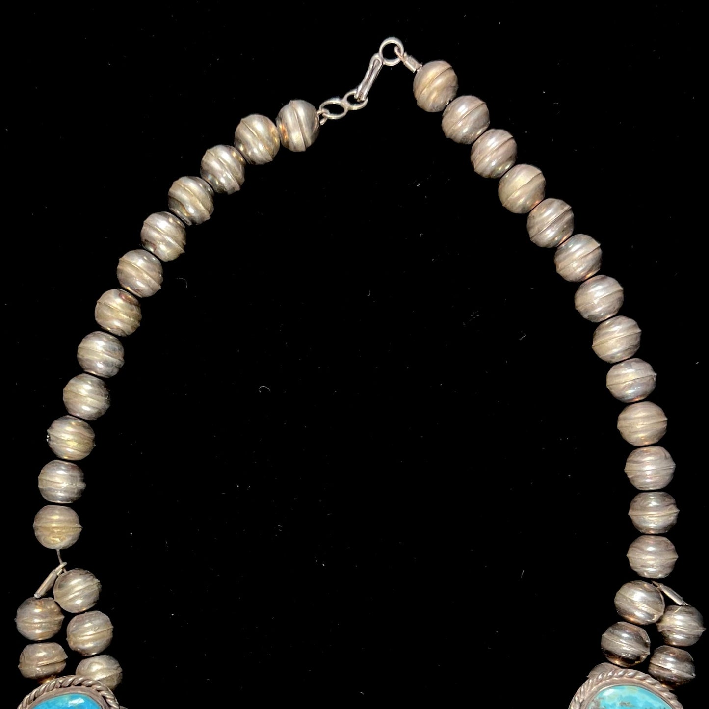 A sterling silver, Navajo style squash blossom necklace set with Morenci turquoise stones.  The legnth is designed for women and children.