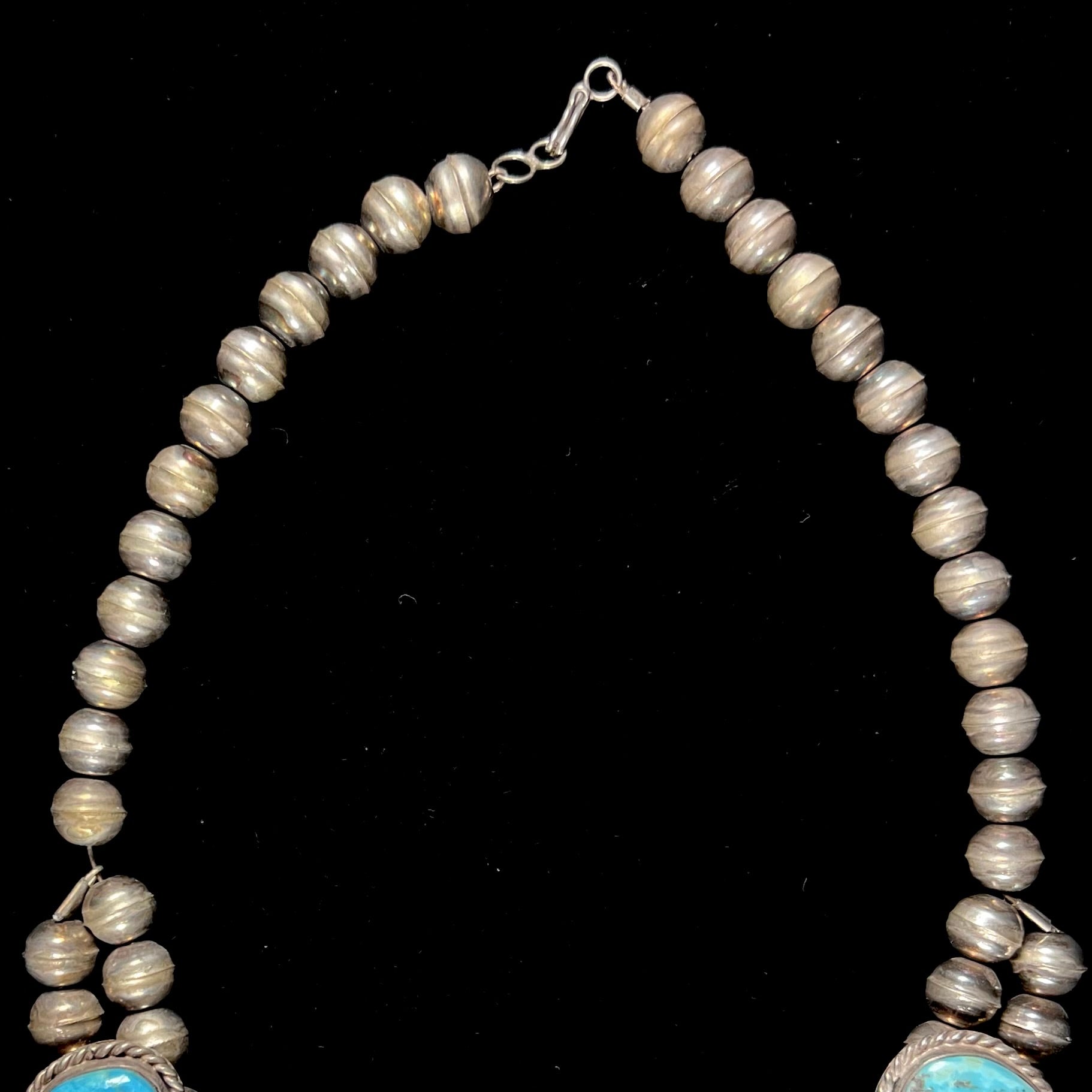 A sterling silver, Navajo style squash blossom necklace set with Morenci turquoise stones.  The legnth is designed for women and children.