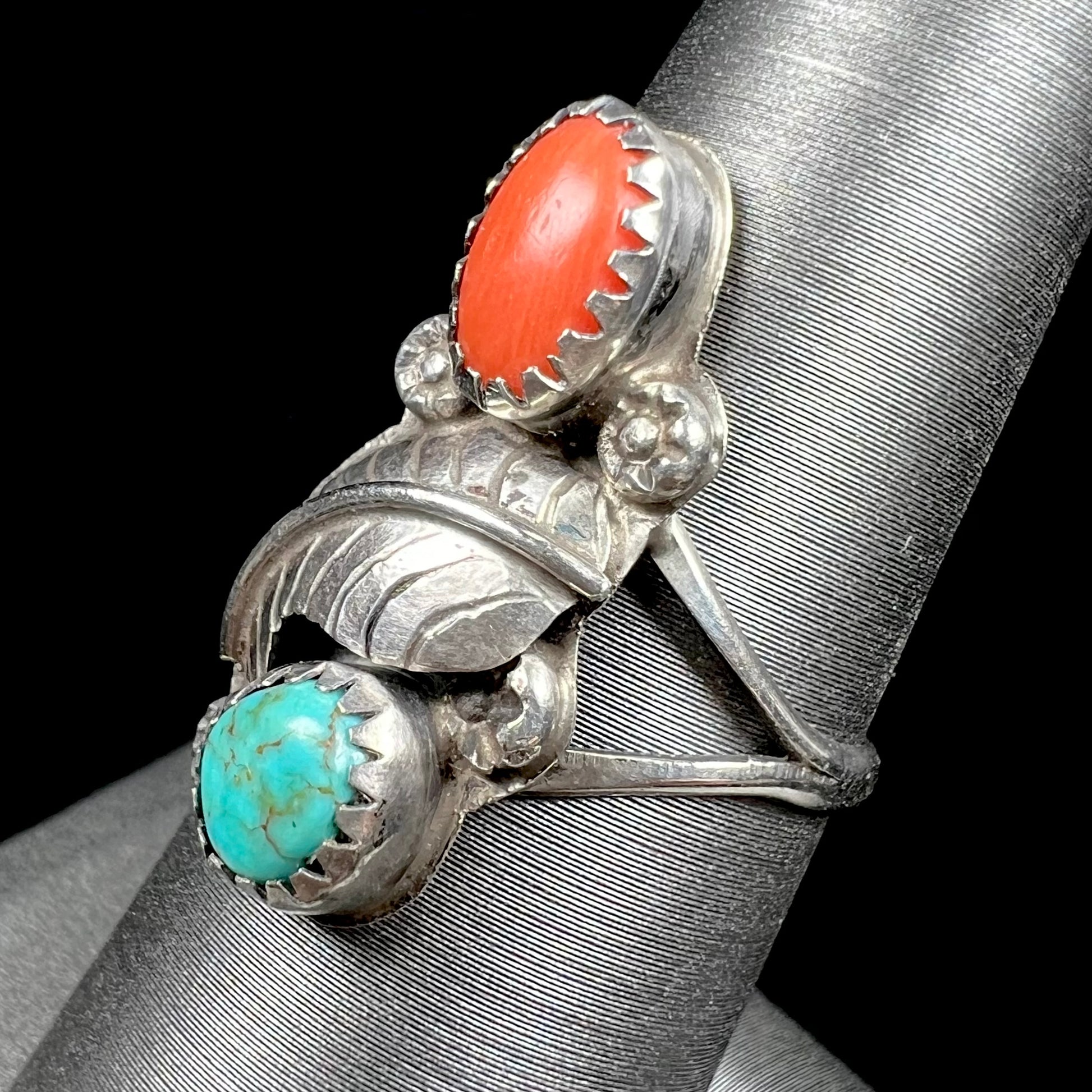 A vintage sterling silver Navajo style ring set with turquoise and coral stones and a feather design.