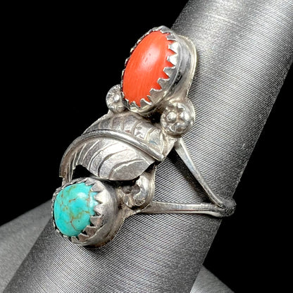 A vintage sterling silver Navajo style ring set with turquoise and coral stones and a feather design.