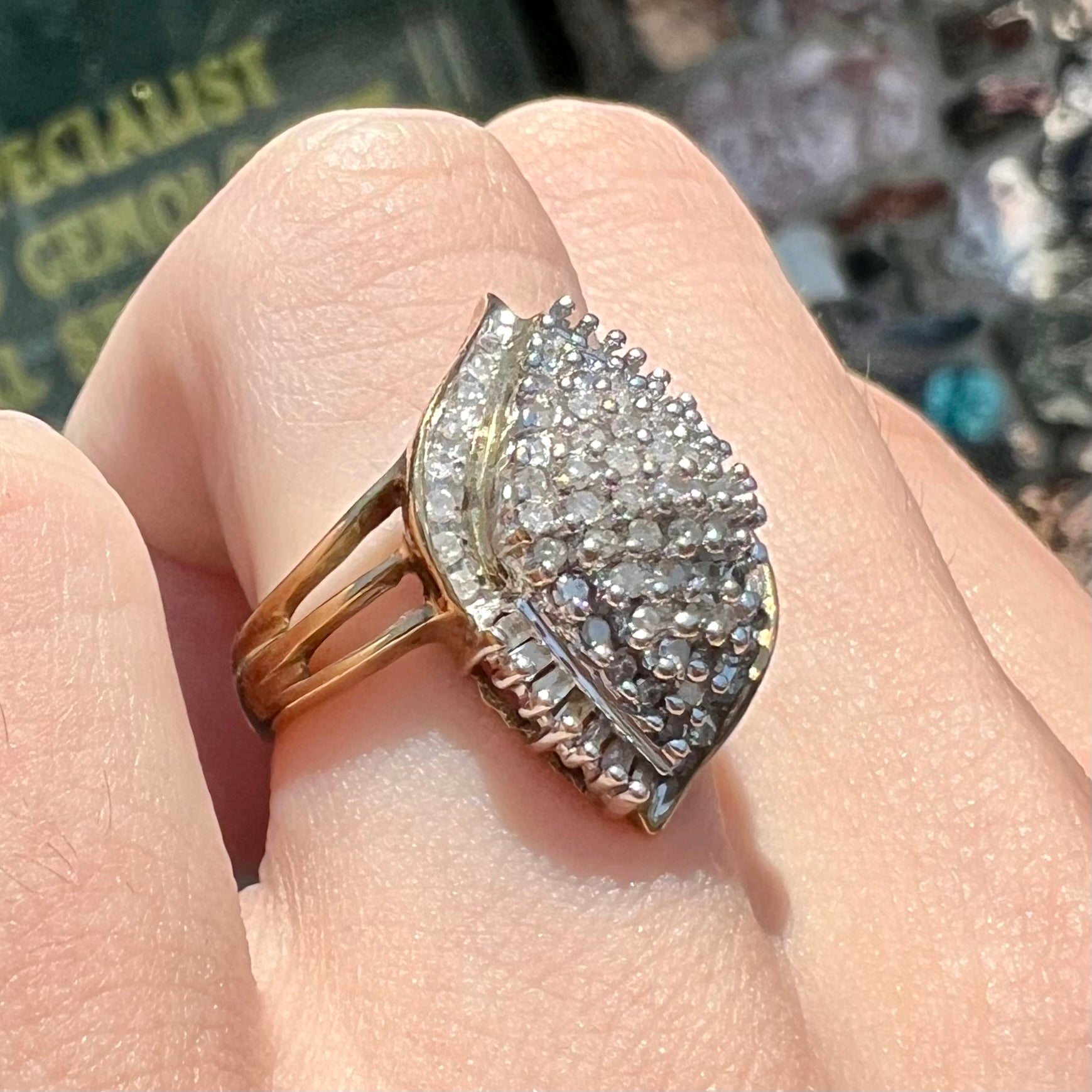 A ladies' yellow gold and diamond cluster ring.  The diamonds are round and baguette shaped, and the ring is navette shaped.