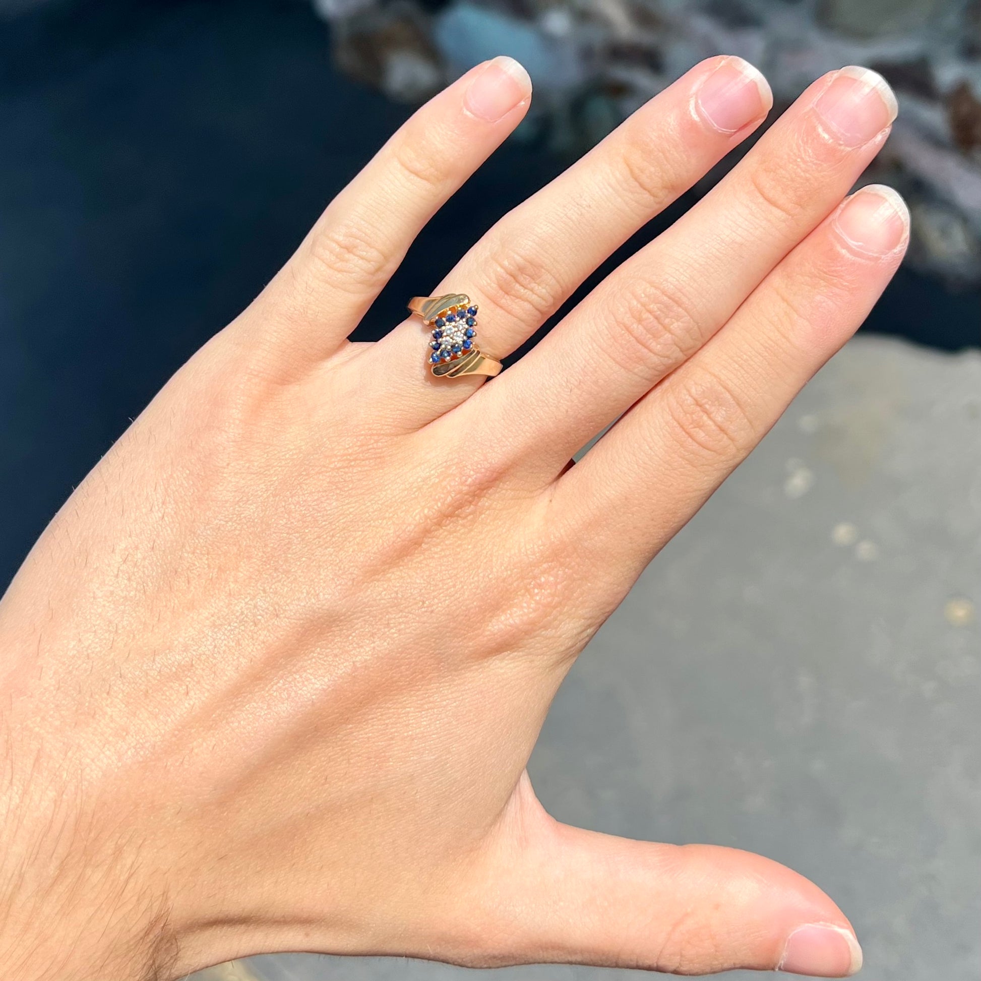 An estate, yellow gold ladies' cluster ring mounted with four round diamonds and twelve round blue sapphires.