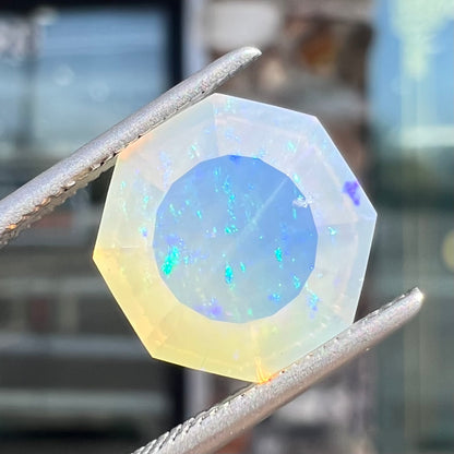 A loose, faceted octagon cut Mexican fire opal gemstone.  The stone is a light yellow color with blue and green fire.