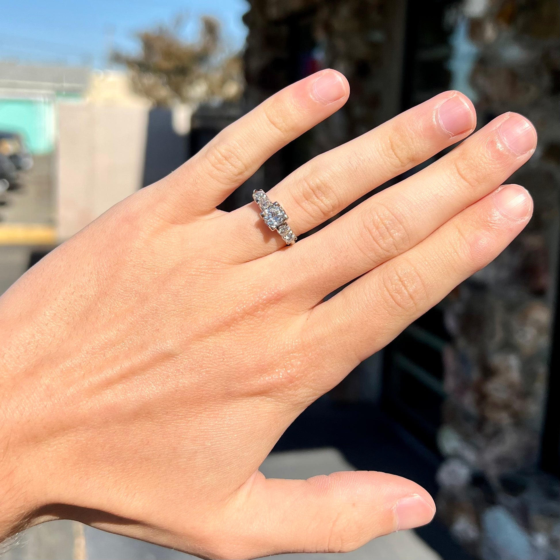 A ladies' 1800's antique white gold diamond ring.  The center stone is an Early American Cut diamond, and the accent stones are Old Mine Cut diamonds.