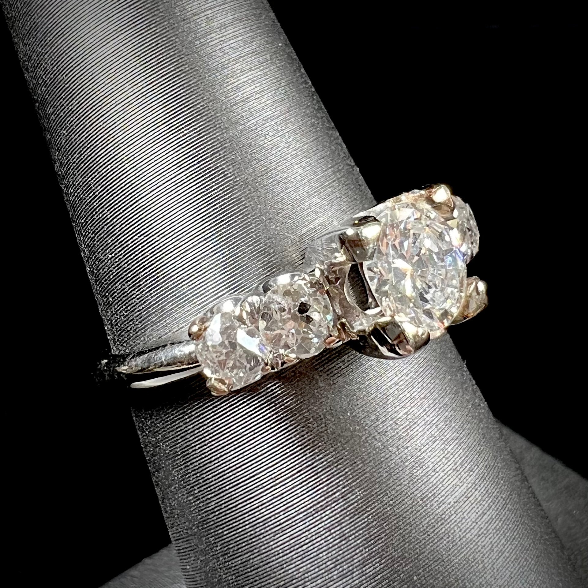 A ladies' 1800's antique white gold diamond ring.  The center stone is an Early American Cut diamond, and the accent stones are Old Mine Cut diamonds.
