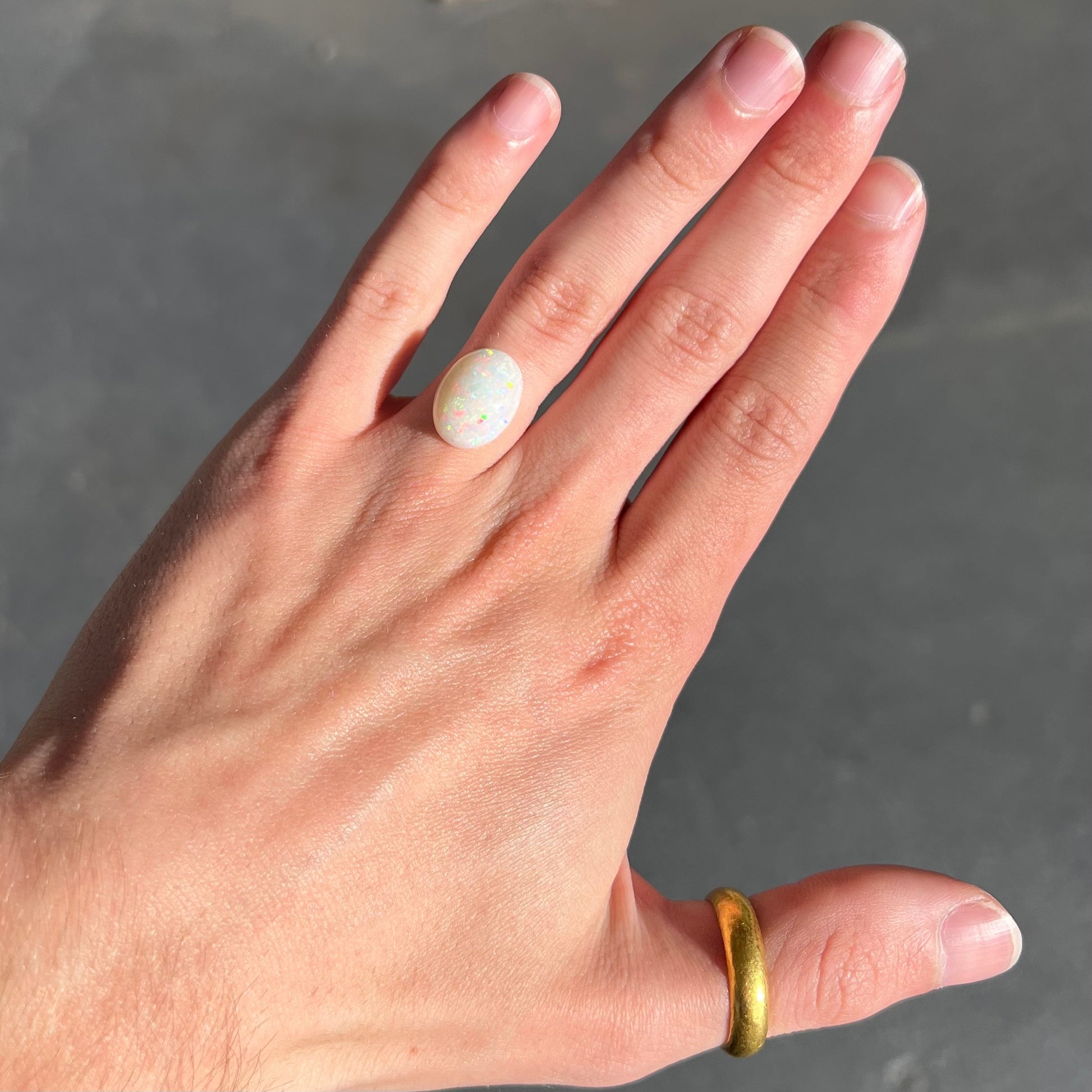 An oval cabochon cut white opal.  The opal has an eye-visible natural fissure inclusion.