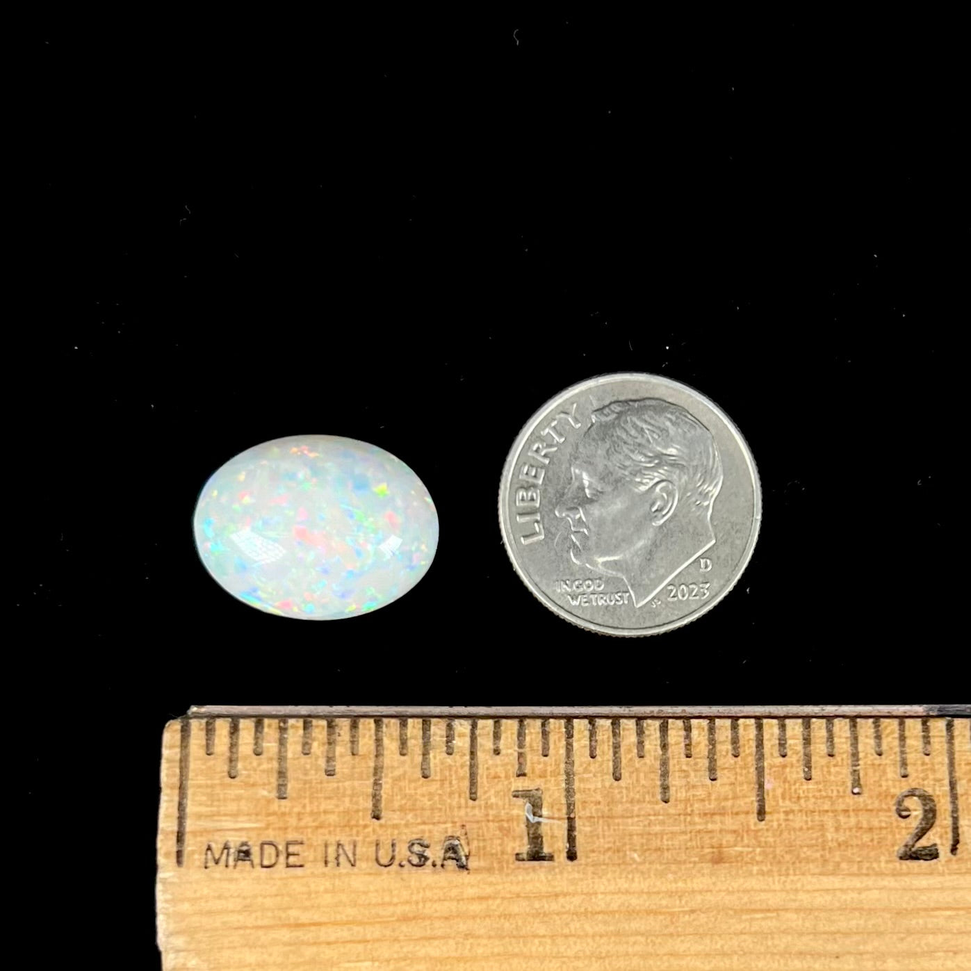 An oval cabochon cut white opal.  The opal has an eye-visible natural fissure inclusion.
