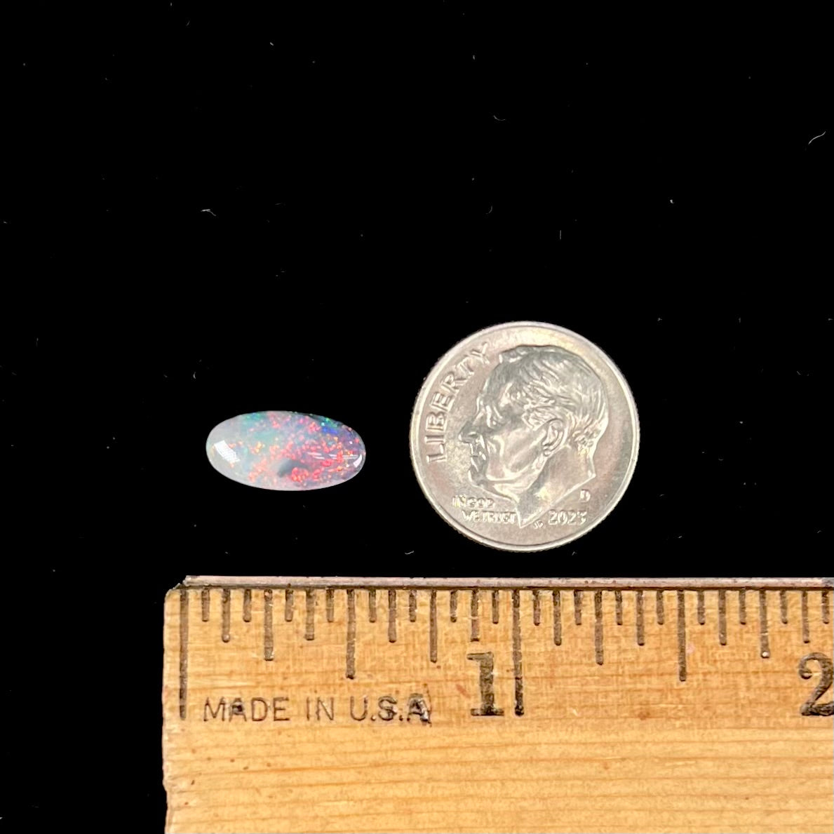A loose, oval cabochon cut opal gemstone from Lightning Ridge, Australia.  The opal shines red and orange colors.