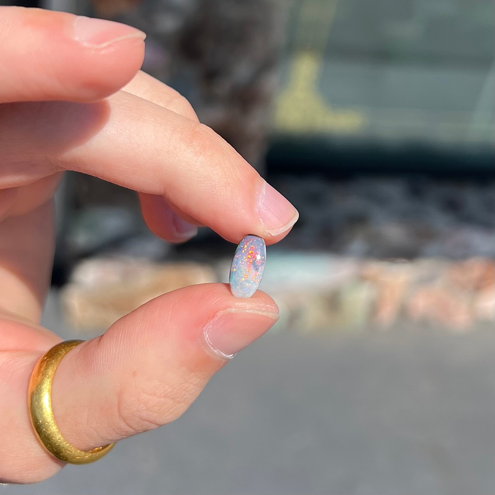 A loose, oval cabochon cut opal gemstone from Lightning Ridge, Australia.  The opal shines red and orange colors.