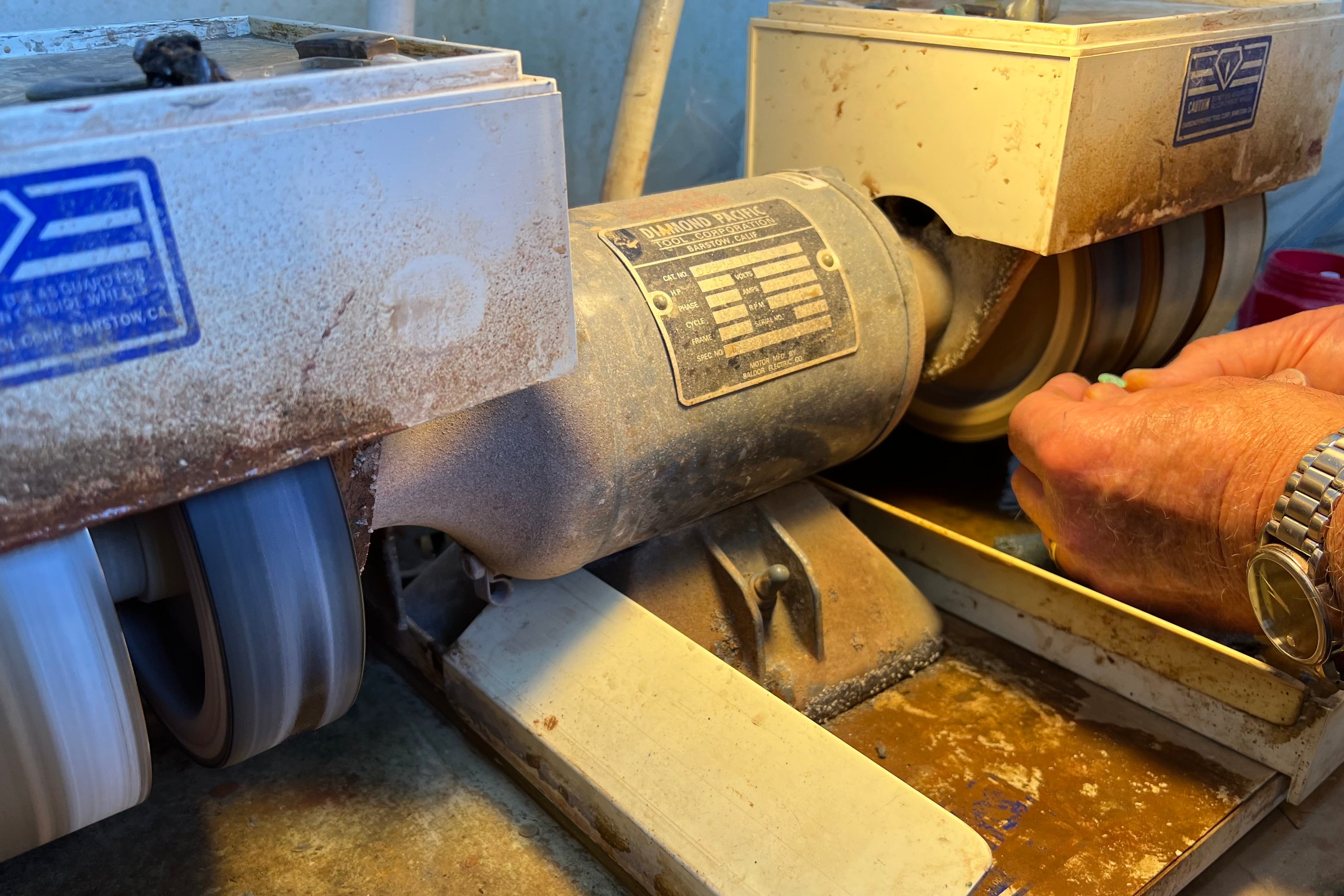 An Anaheim, California lapidarist finishes polishing a loose opal stone on a Genie cutting wheel.