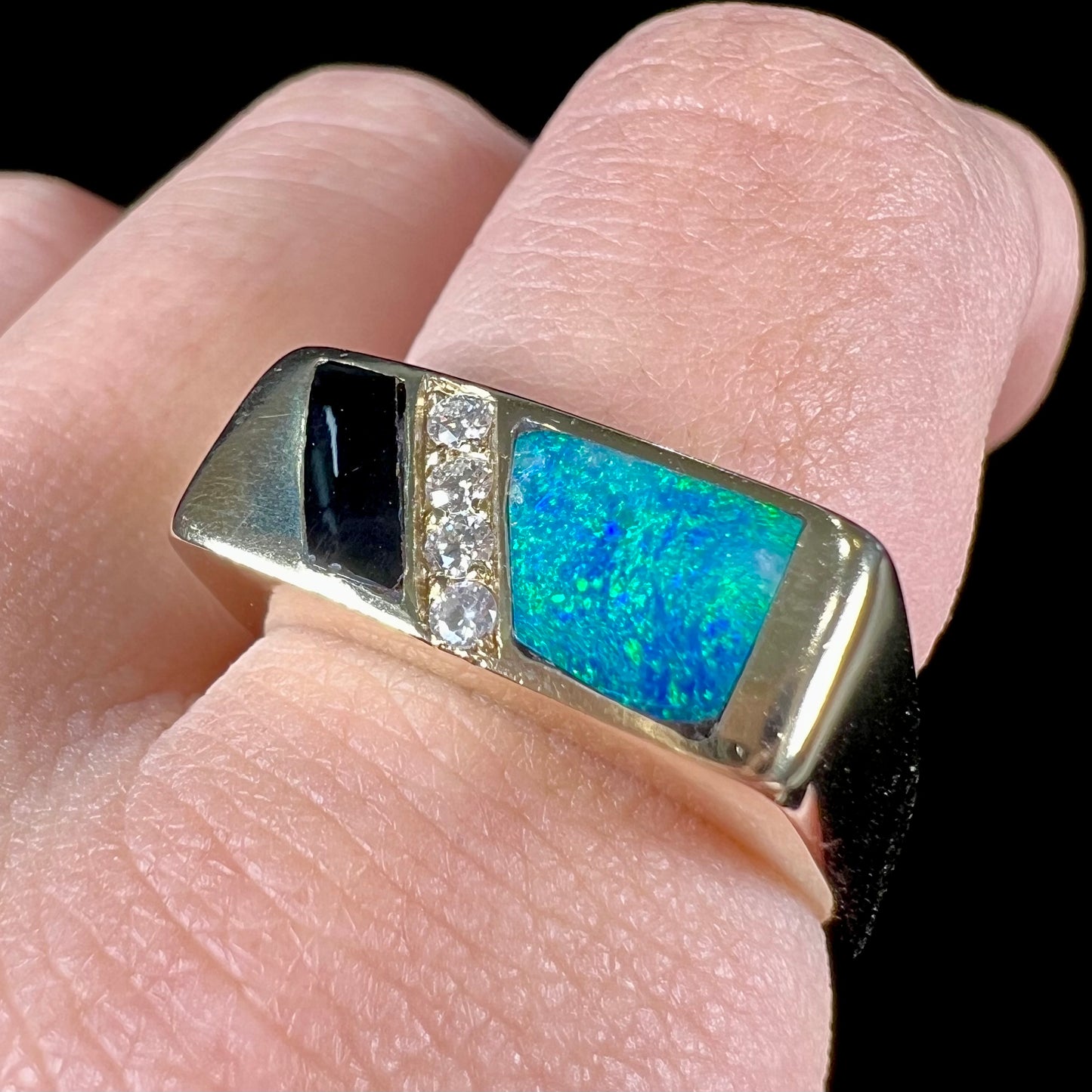 A men's yellow gold ring inlay set with onyx, natural black opal, and four diamonds.