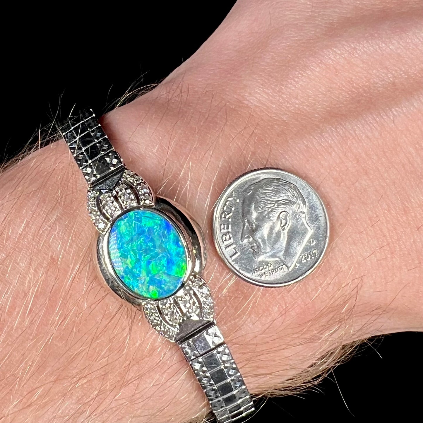 A ladies' art deco style white gold and stainless steel bracelet set with a natural black opal doublet and diamonds.