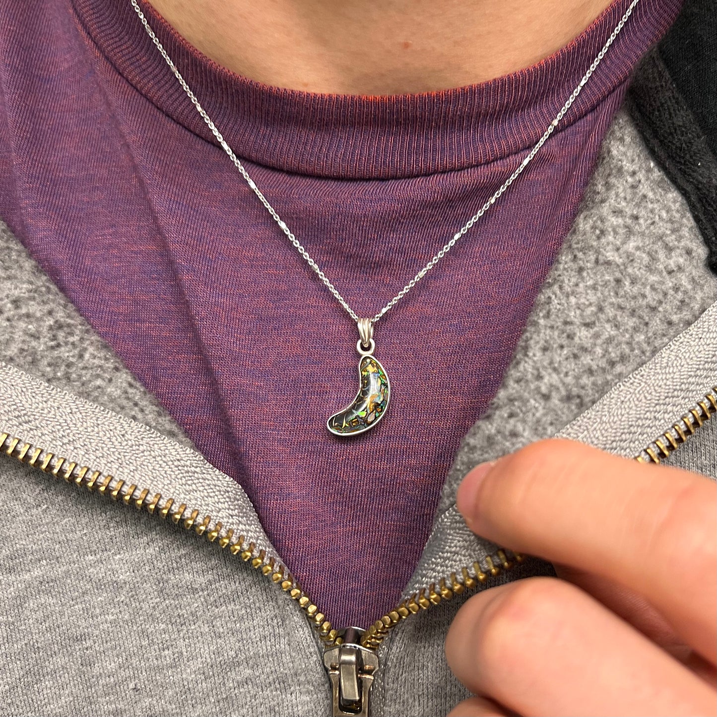 A sterling silver necklace bezel set with a natural Koroit boulder opal stone.  The stone is shaped like a crescent moon.