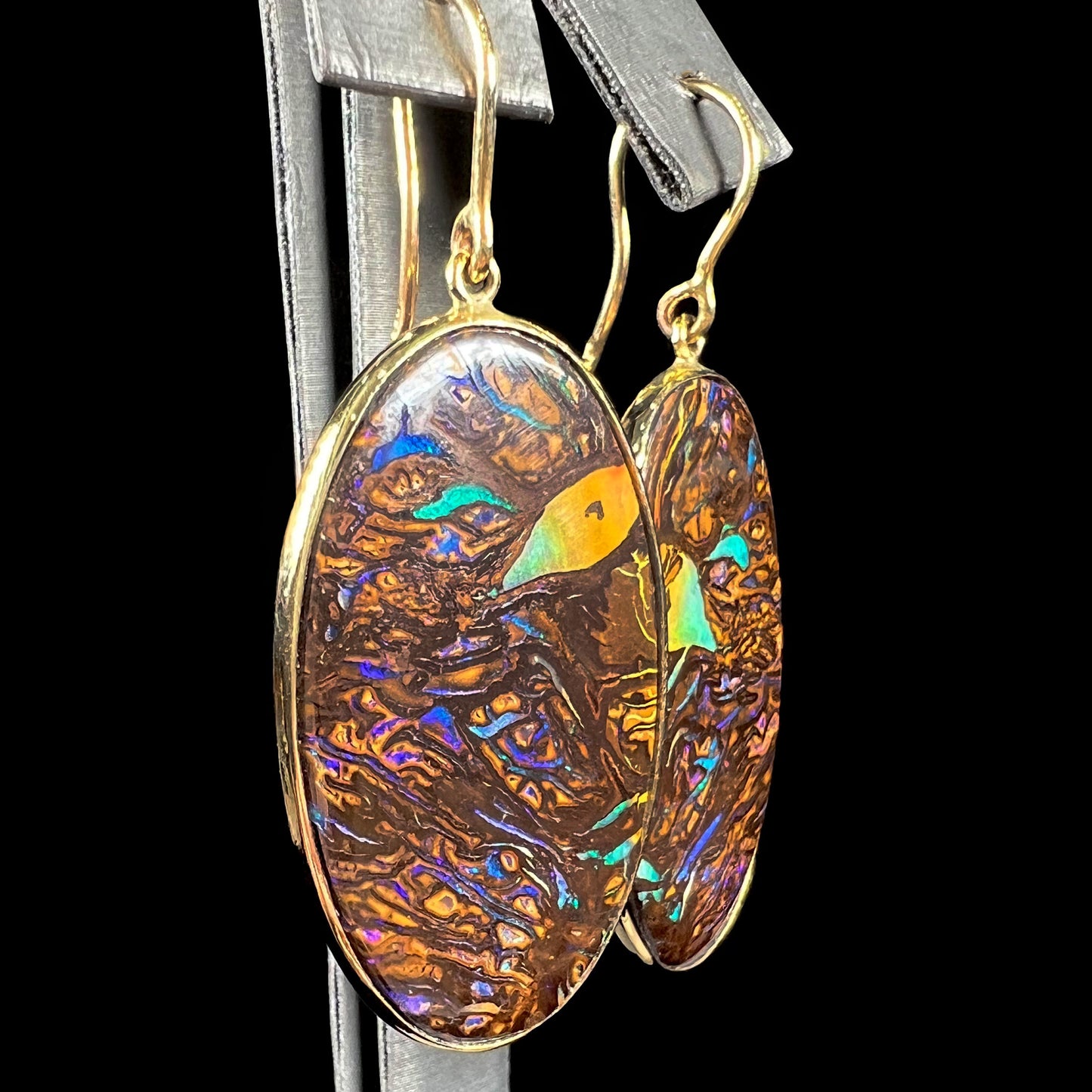 A pair of Koroit boulder opal dangle earrings set in yellow gold bezels.