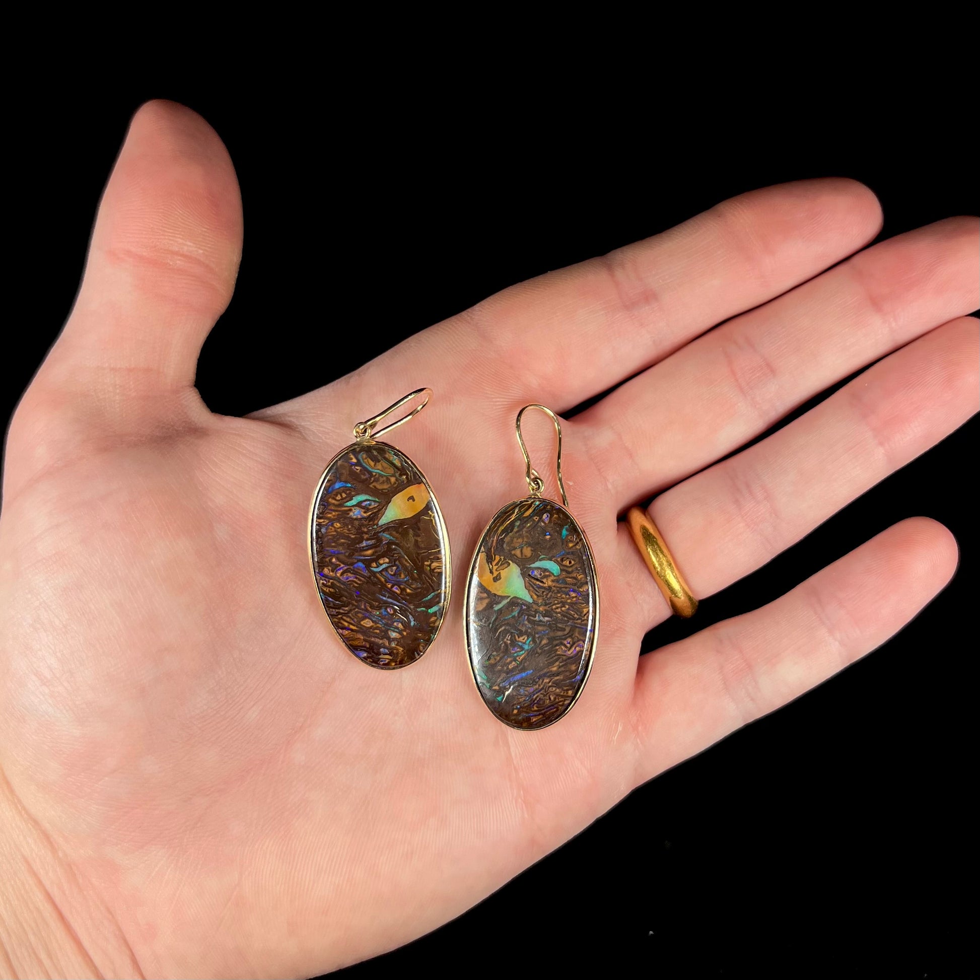 A pair of Koroit boulder opal dangle earrings set in yellow gold bezels.