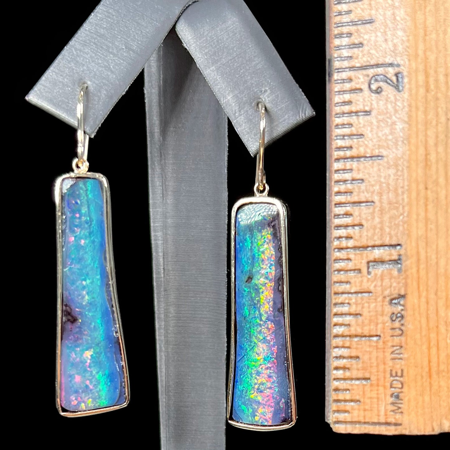 A pair of natural boulder opal dangle earrings set in yellow gold.  The opal displays a rainbow of colors and is from Bull Creek, Australia.