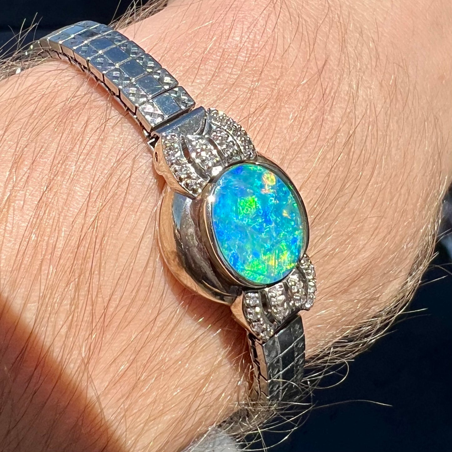 A ladies' art deco style white gold and stainless steel bracelet set with a natural black opal doublet and diamonds.