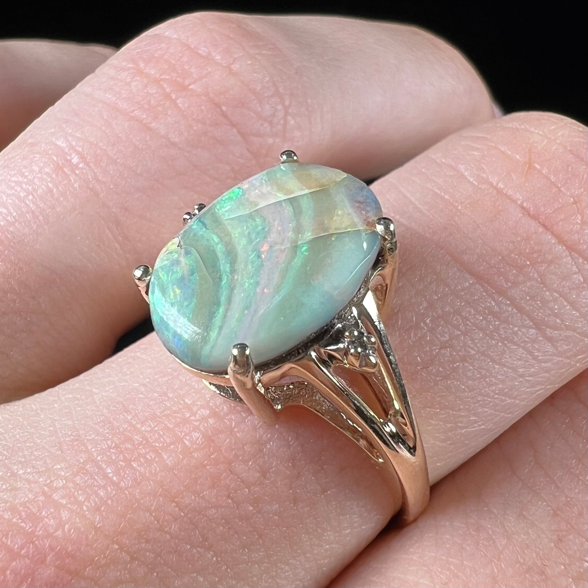 A ladies' Australian boulder opal ring set in yellow gold with diamond accents.  The opal shimmers green and pink and has fissure inclusions.