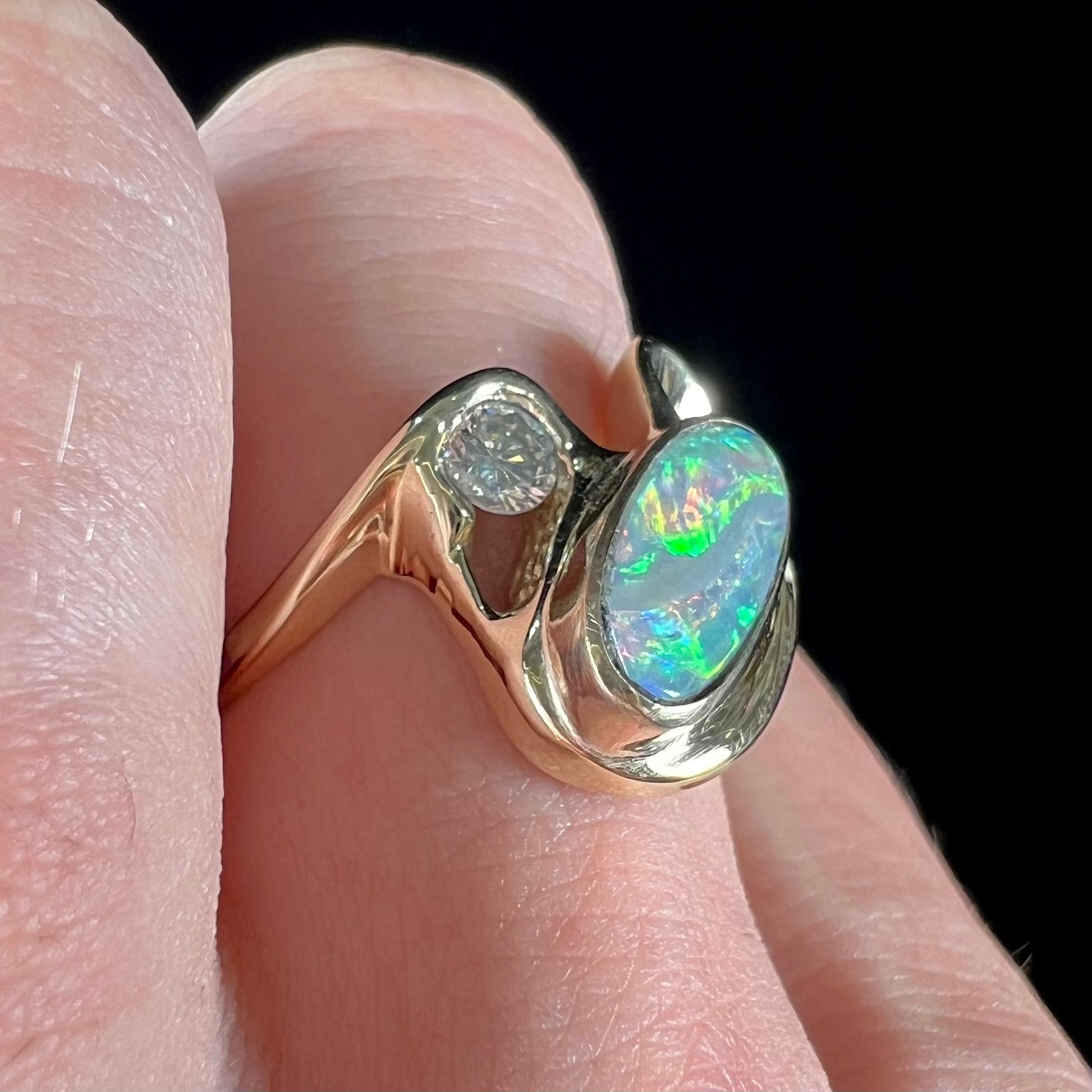 A ladies' yellow gold, bezel set ring mounted with a natural 1.15 carat black opal and round diamond.