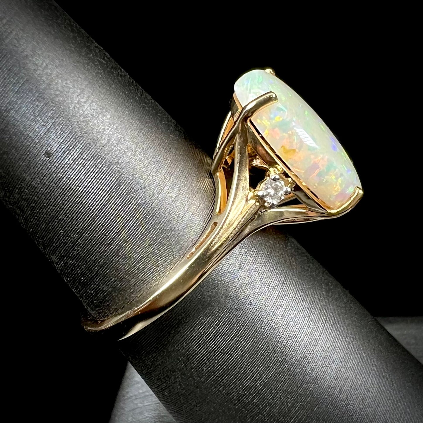 A ladies' yellow gold ring set with two diamonds and an oval cut natural opal stone.