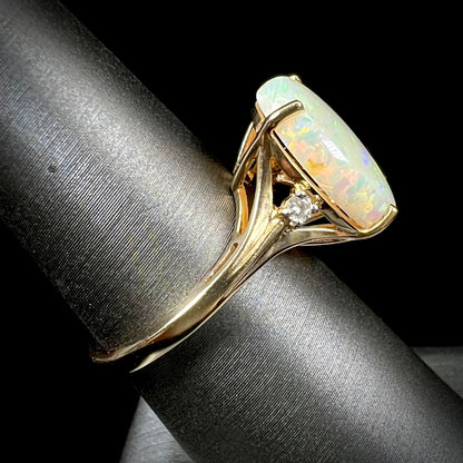 A ladies' yellow gold ring set with two diamonds and an oval cut natural opal stone.