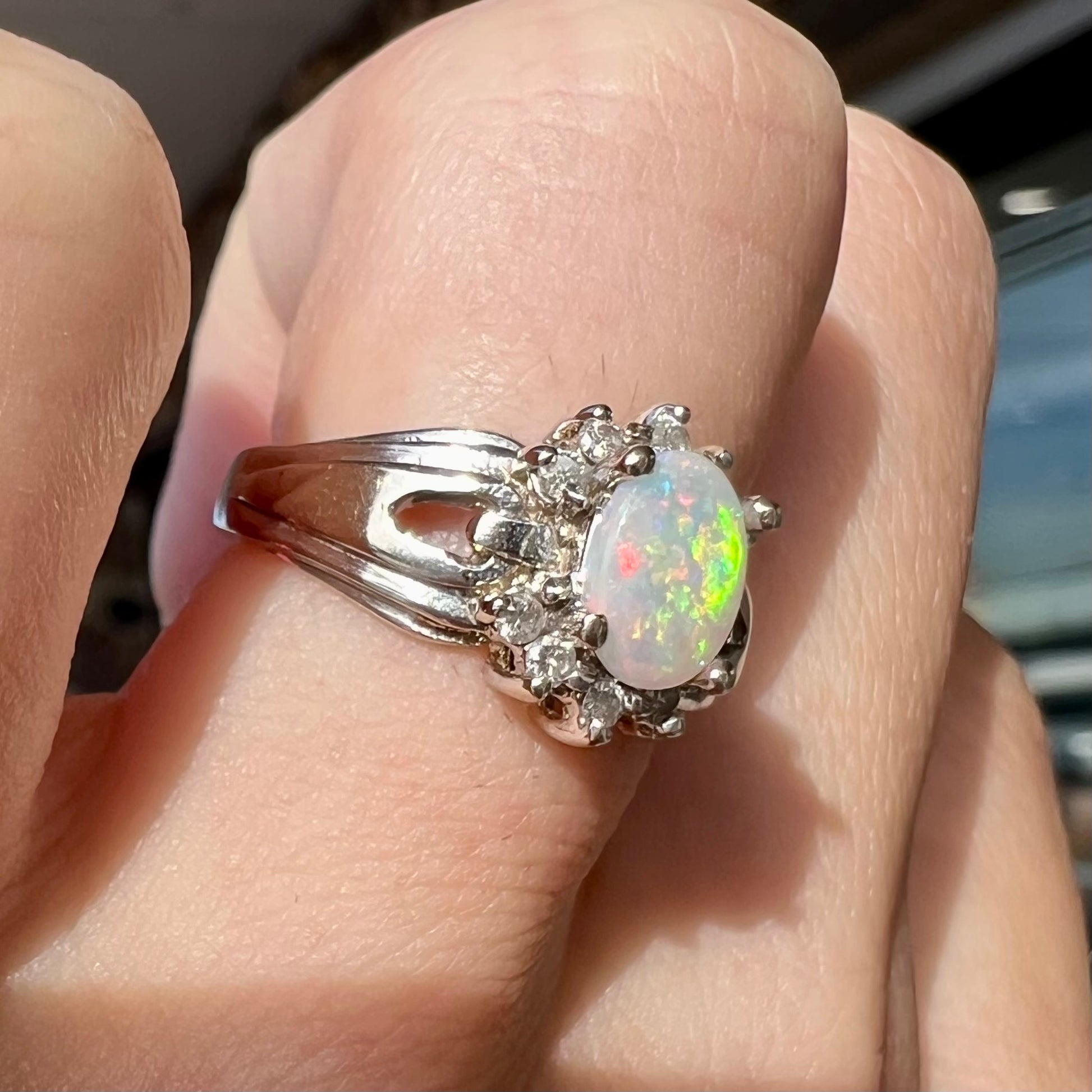 A ladies' white gold ring set with a halo of diamonds and an oval cabochon cut Australian opal.