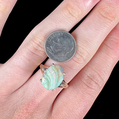 A ladies' Australian boulder opal ring set in yellow gold with diamond accents.  The opal shimmers green and pink and has fissure inclusions.