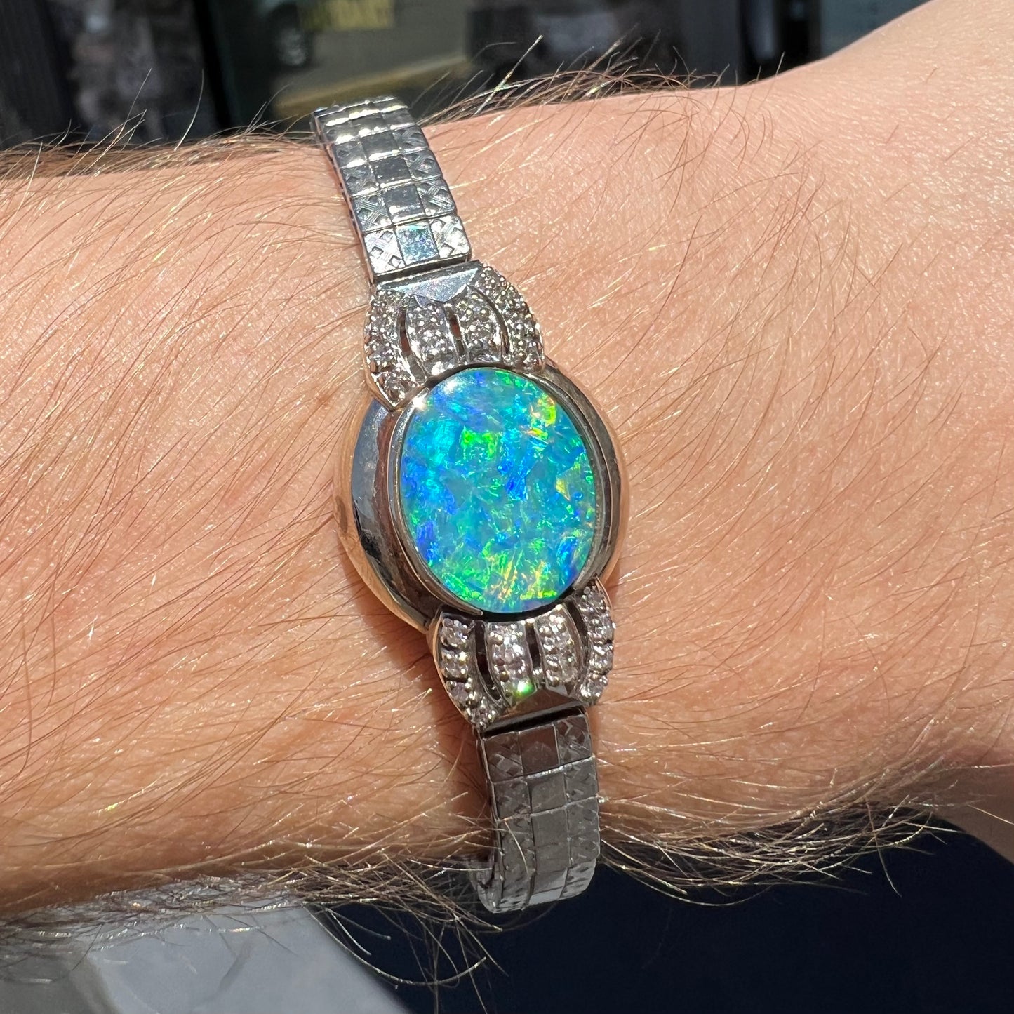 A ladies' art deco style white gold and stainless steel bracelet set with a natural black opal doublet and diamonds.