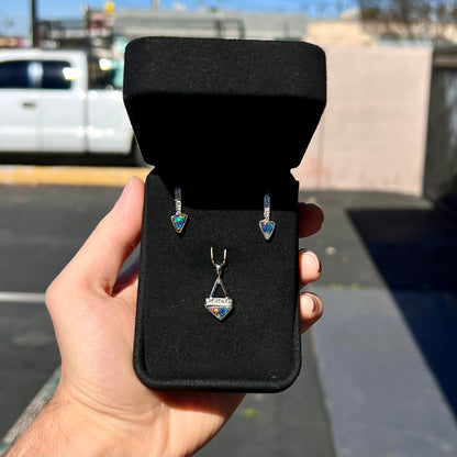 A white gold pendant and earrings set mounted with triangle cut natural black opals and diamonds.