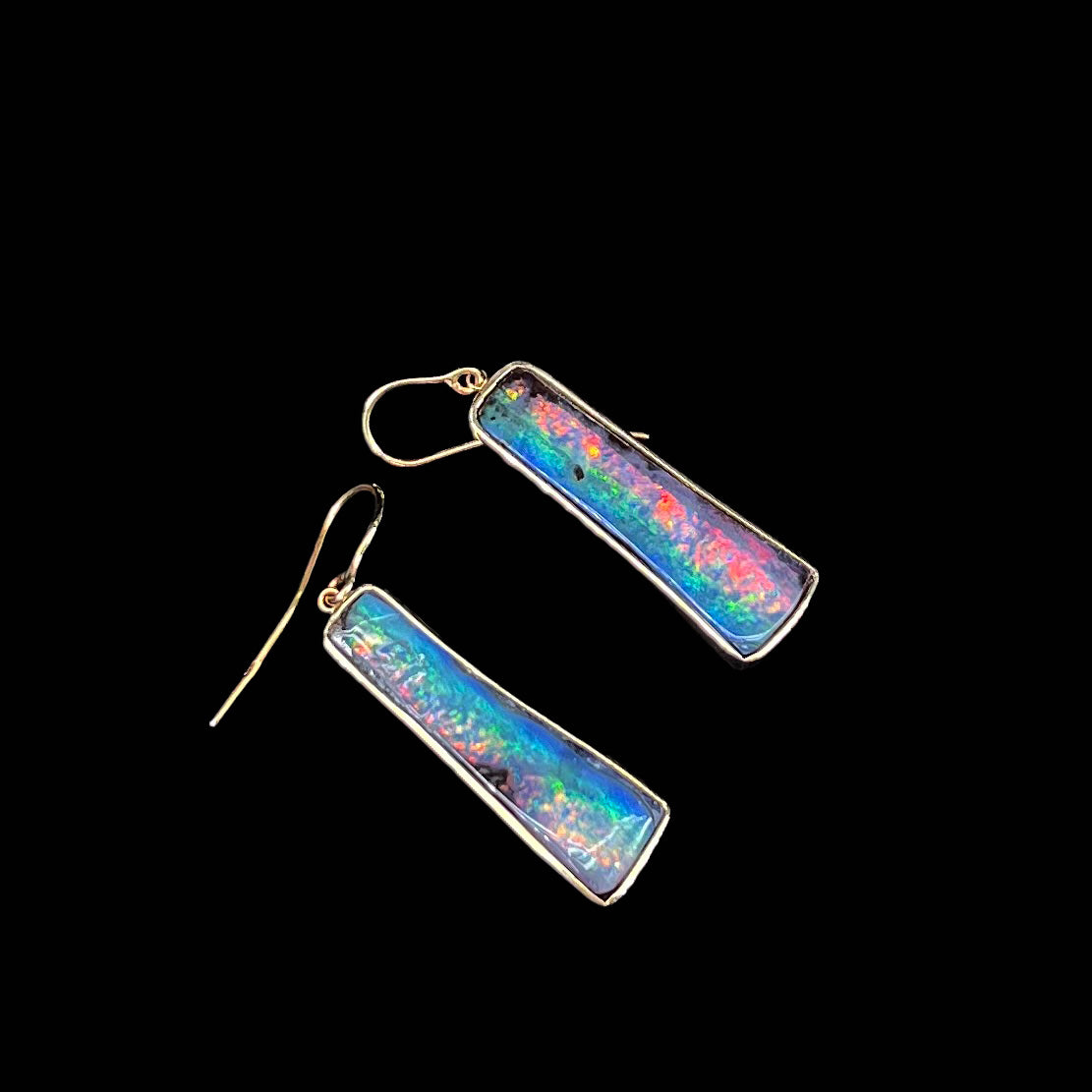 A pair of natural boulder opal dangle earrings set in yellow gold.  The opal displays a rainbow of colors and is from Bull Creek, Australia.