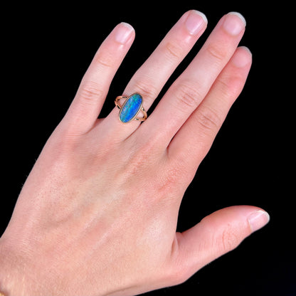 A ladies' yellow gold split shank solitaire ring set with a natural Australian black boulder opal.