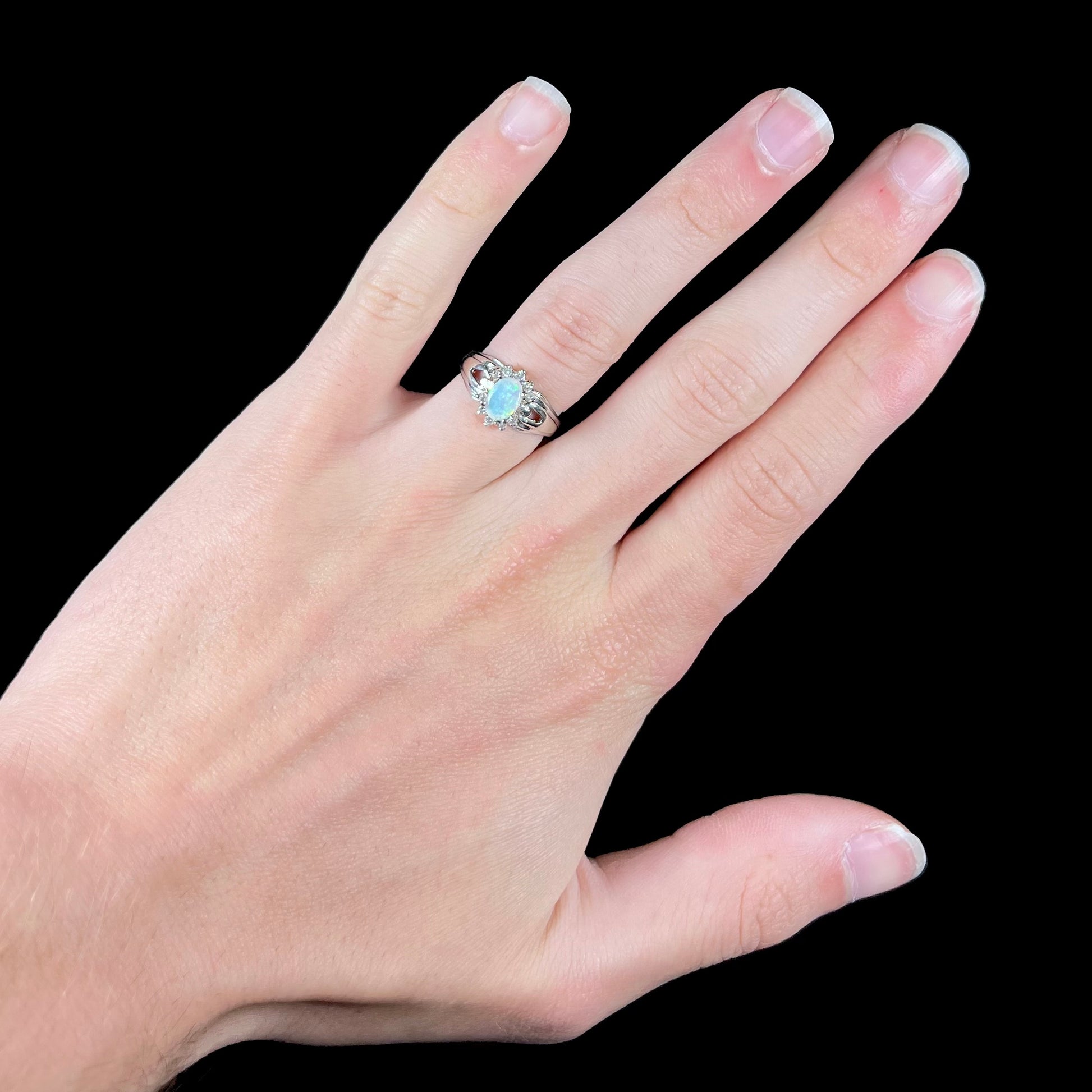 A ladies' white gold ring set with a halo of diamonds and an oval cabochon cut Australian opal.