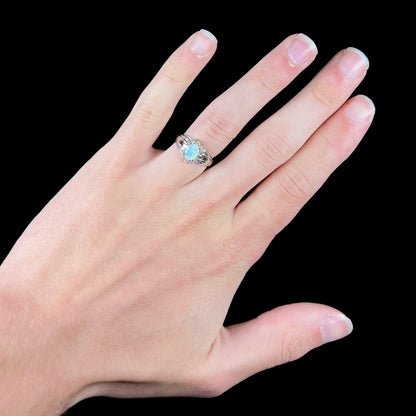 A ladies' white gold ring set with a halo of diamonds and an oval cabochon cut Australian opal.