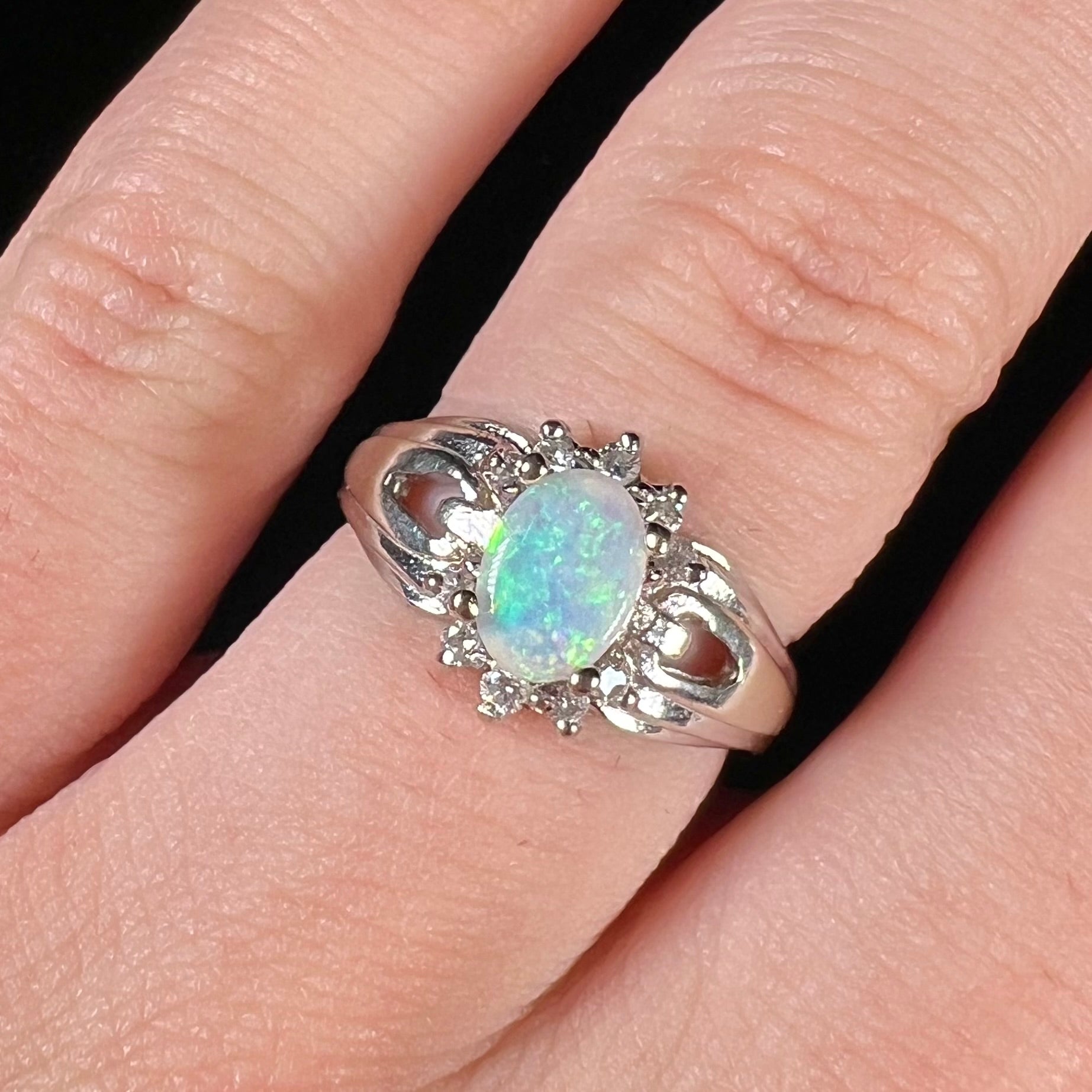 A ladies' white gold ring set with a halo of diamonds and an oval cabochon cut Australian opal.