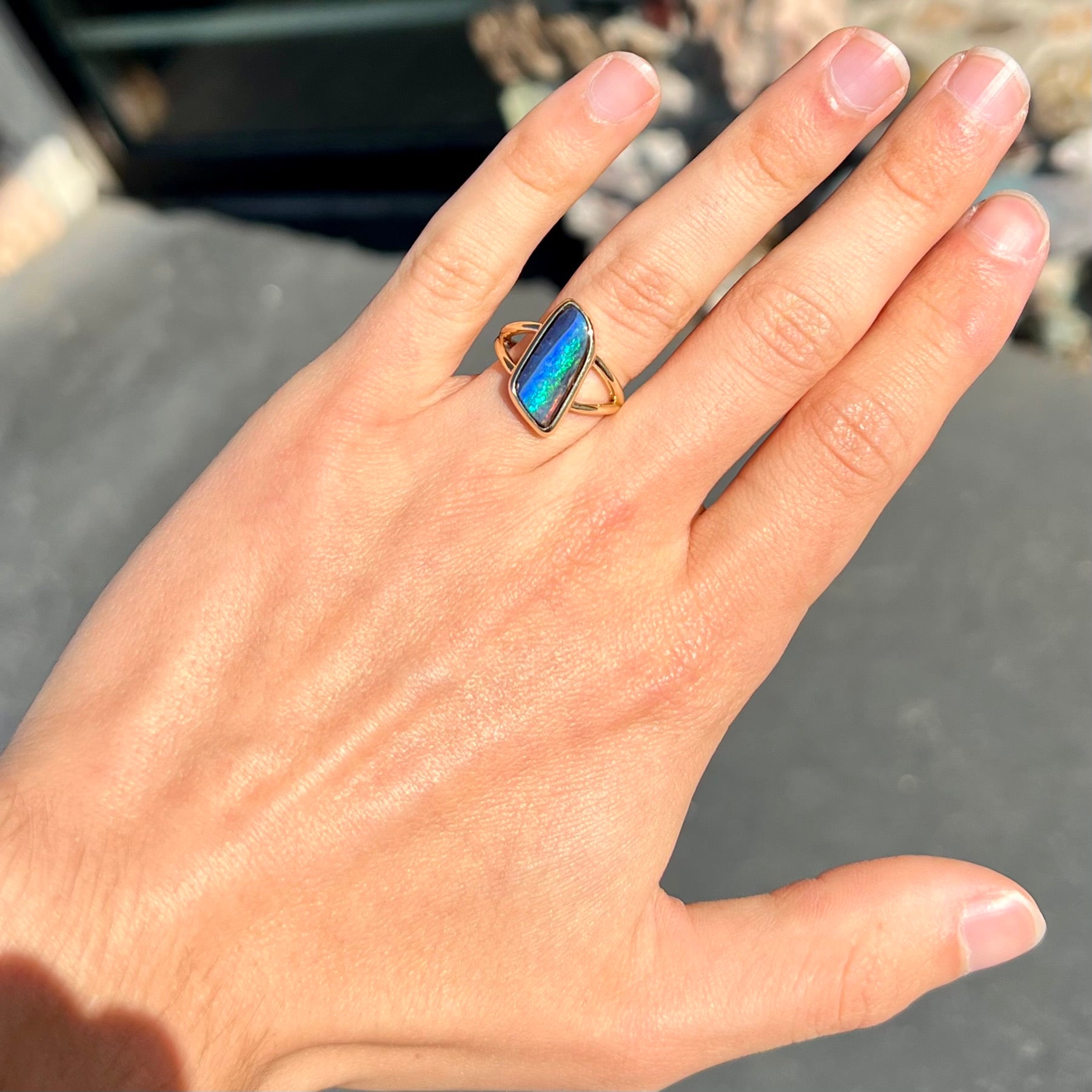 A ladies' split shank gold ring bezel set with a natural, Australian black boulder opal.