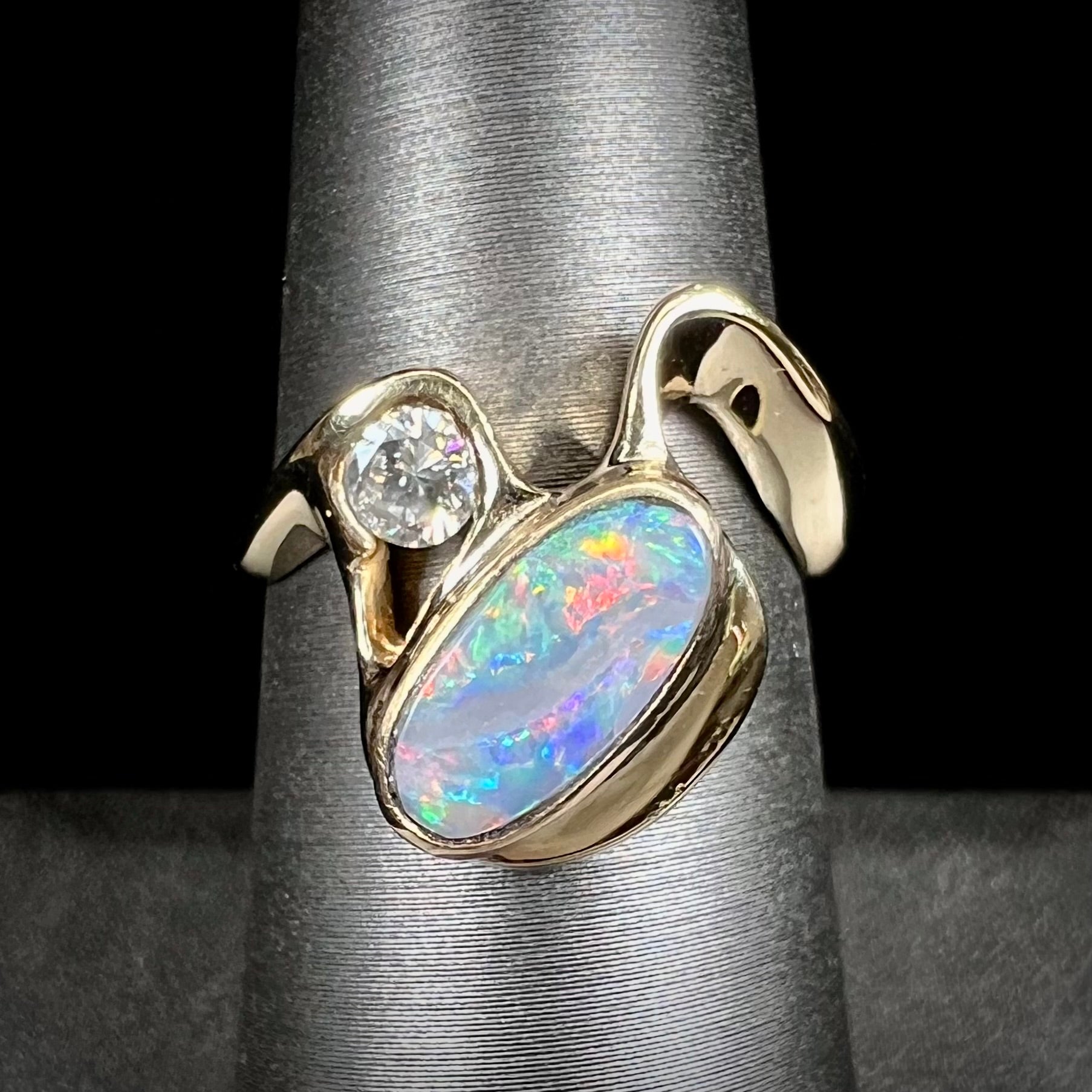 A ladies' yellow gold, bezel set ring mounted with a natural 1.15 carat black opal and round diamond.