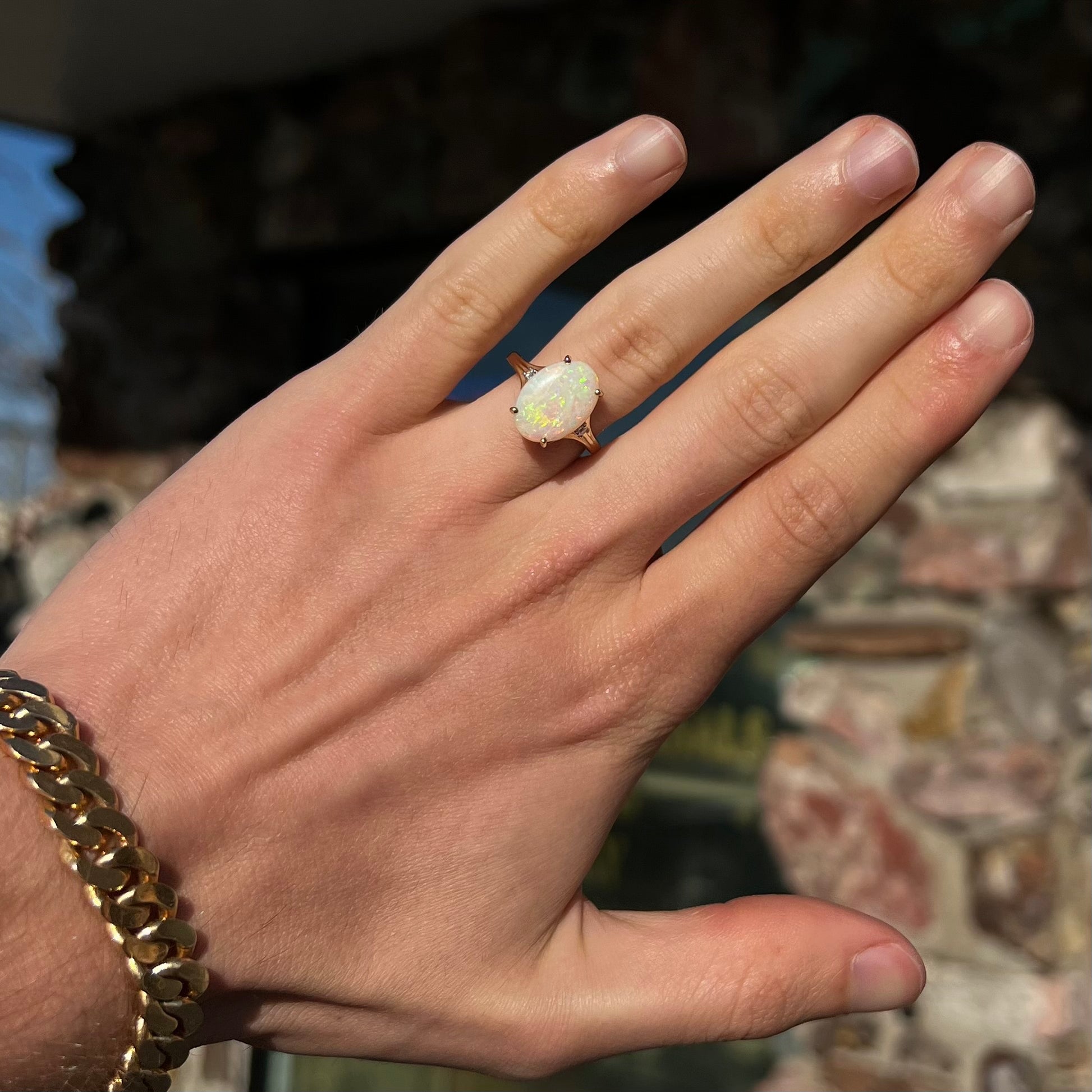 A ladies' yellow gold ring set with two diamonds and an oval cut natural opal stone.