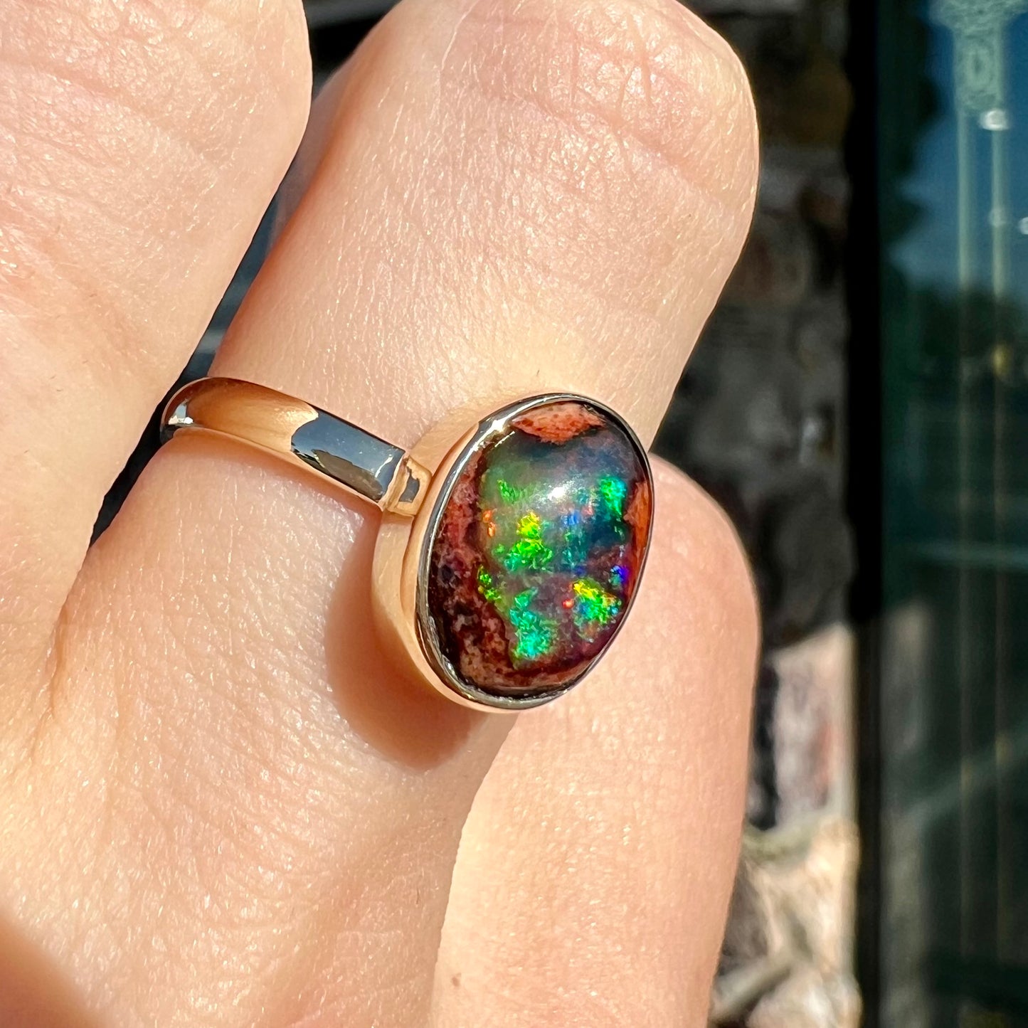 A ladies' yellow gold solitaire ring bezel set with an oval cabochon cut natural black Mexican cantera fire opal stone.