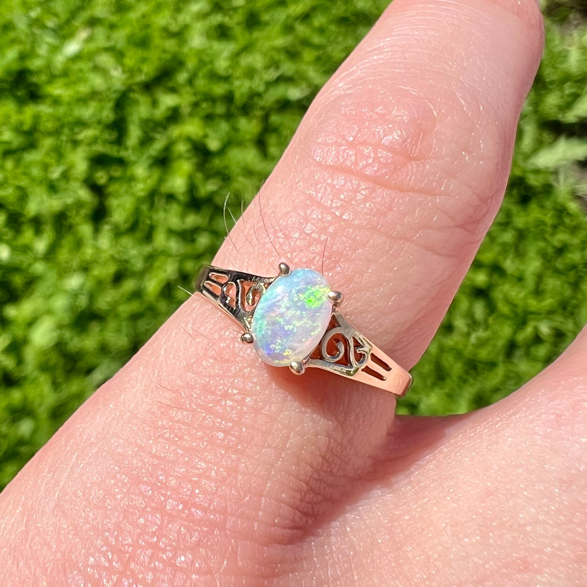 A ladies' natural opal in gold filigree ring.  The opal shines with colors of green and blue.