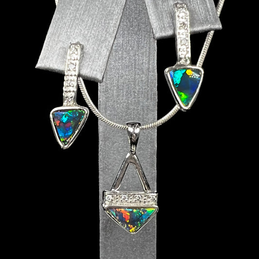 A white gold pendant and earrings set mounted with triangle cut natural black opals and diamonds.