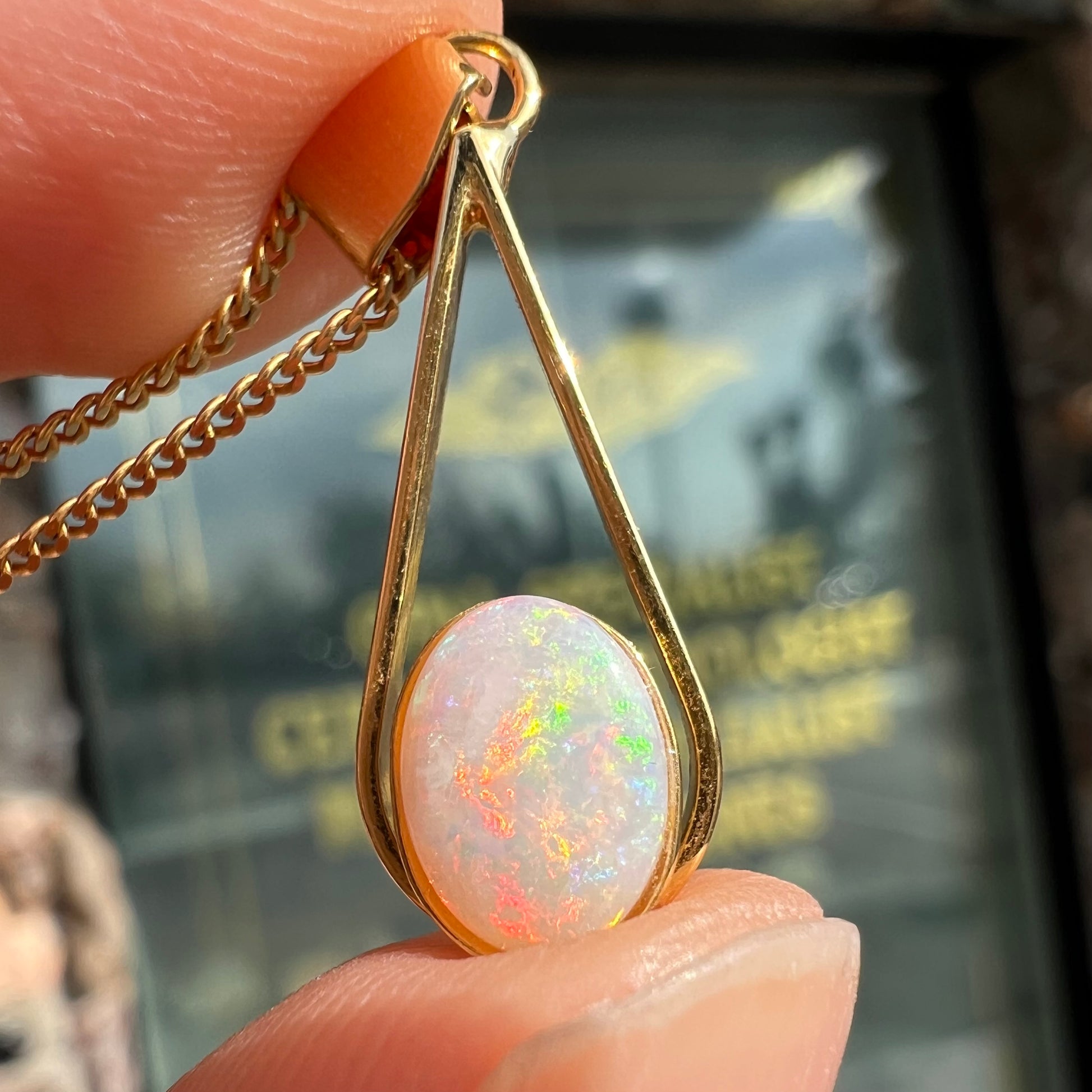 A gold plated necklace set with a natural white crystal opal.  The opal shines pinkish red and blue colors.