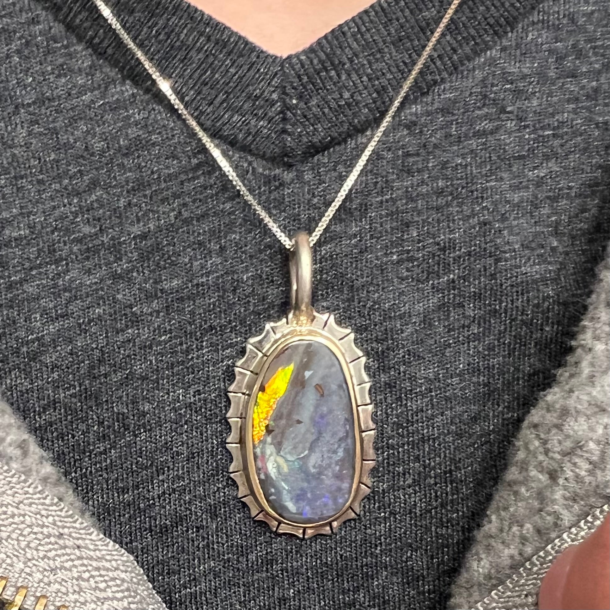 A Southwest style two-tone sterling silver pendant set with a black boulder opal with a yellow gold bezel.