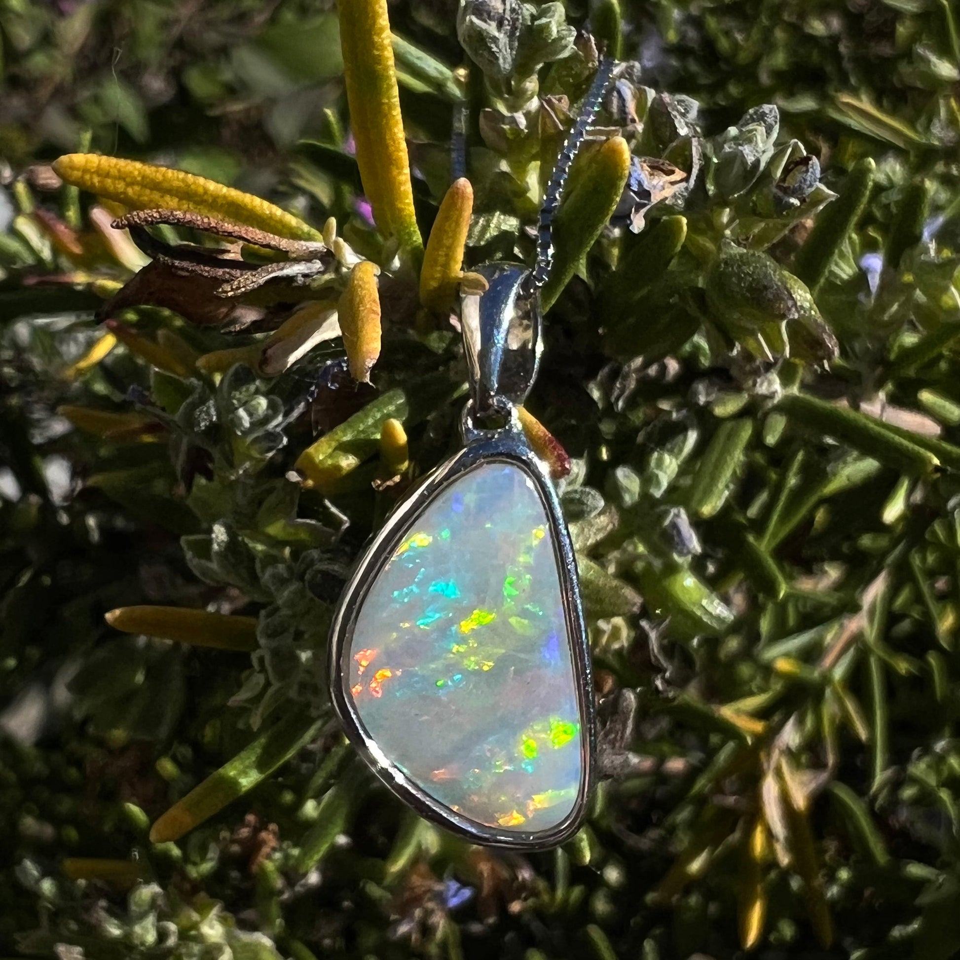 A sterling silver pendant bezel set with a white Australian crystal opal on a box chain.