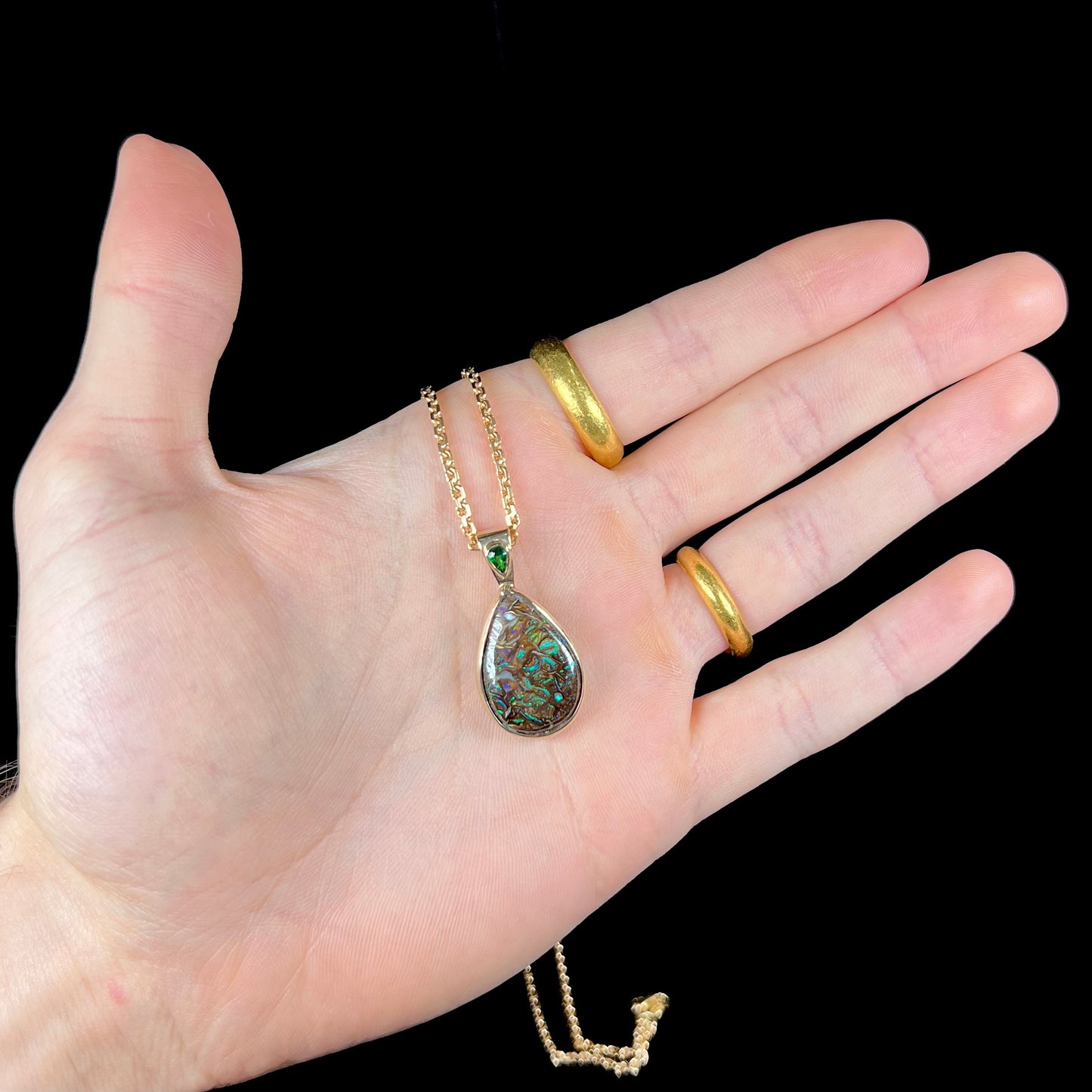 A ladies' yellow gold pendant set with a natural Koroit, Australian boulder opal and a tsavorite garnet accent stone.
