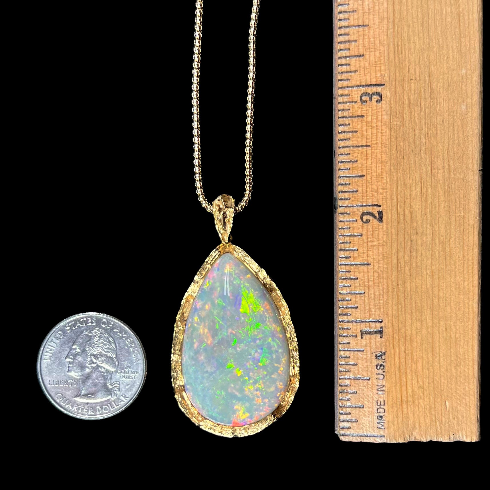 A ladies' natural, pear shaped, gray base Australian opal pendant set in 18 karat yellow gold.