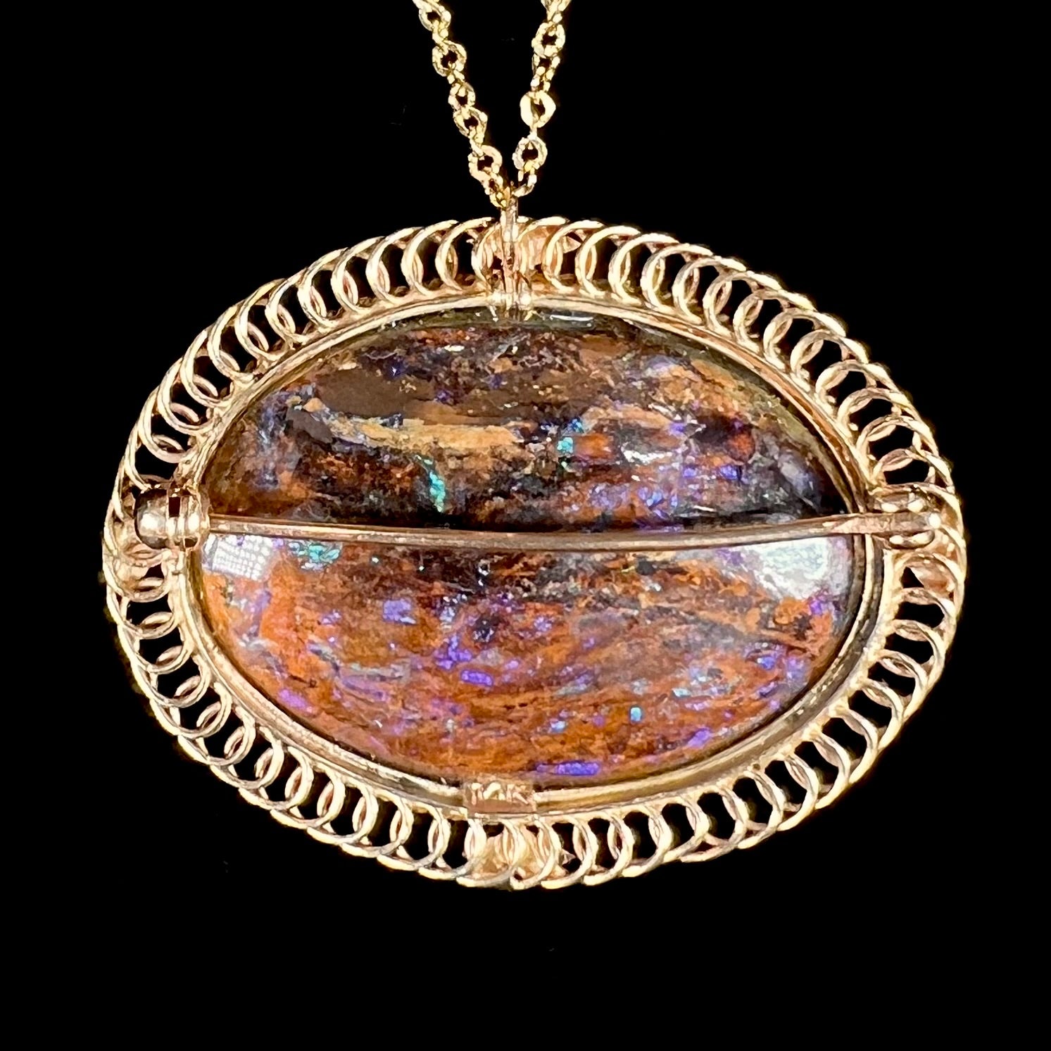 A yellow gold filigree style brooch/pendant combination piece set with a purple opalized wood stone from Duck Creek, Australia.