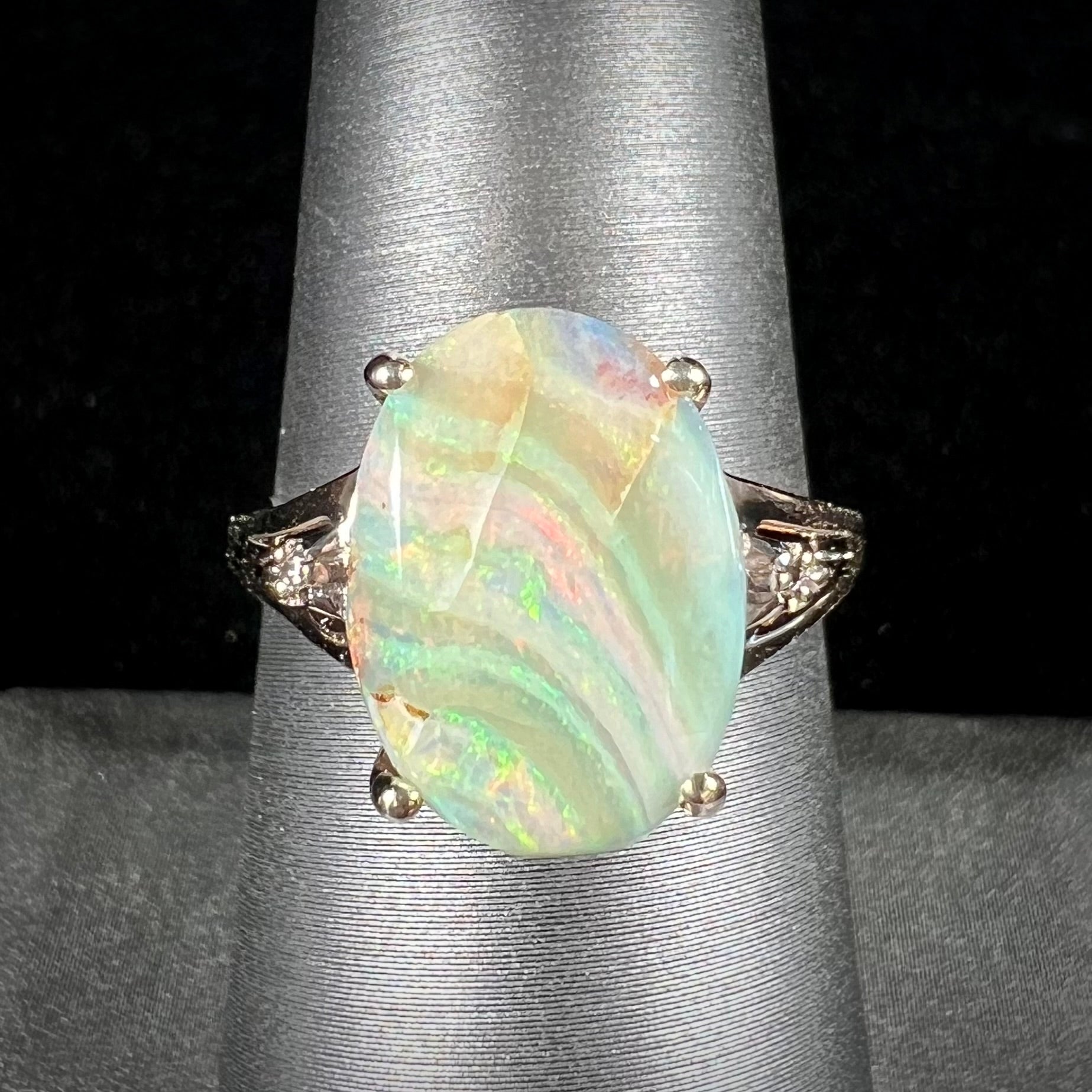 A ladies' Australian boulder opal ring set in yellow gold with diamond accents.  The opal shimmers green and pink and has fissure inclusions.