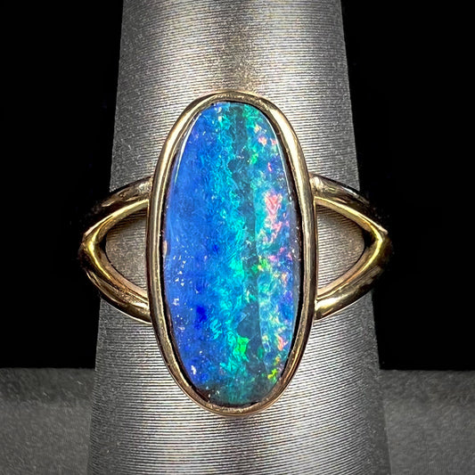 A ladies' yellow gold split shank solitaire ring set with a natural Australian black boulder opal.