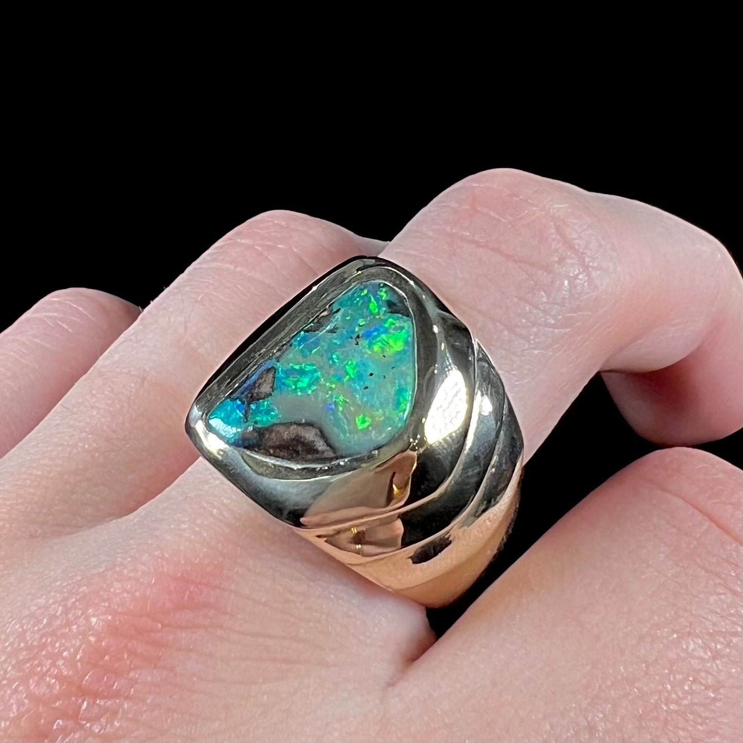 A men's yellow gold solitaire ring set with a triangular shaped natural boulder opal.